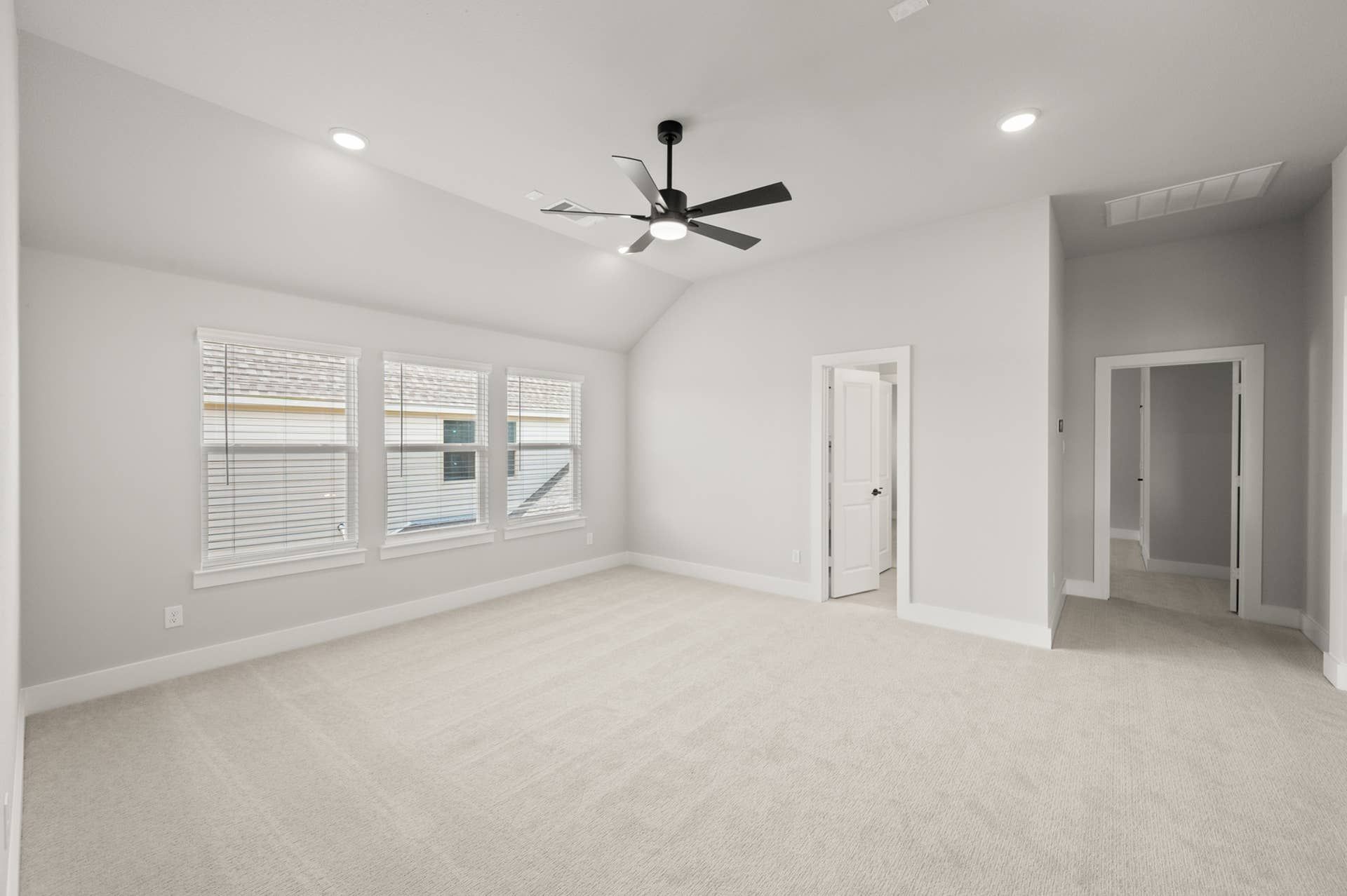 Spacious game room with large windows and modern ceiling fan.
