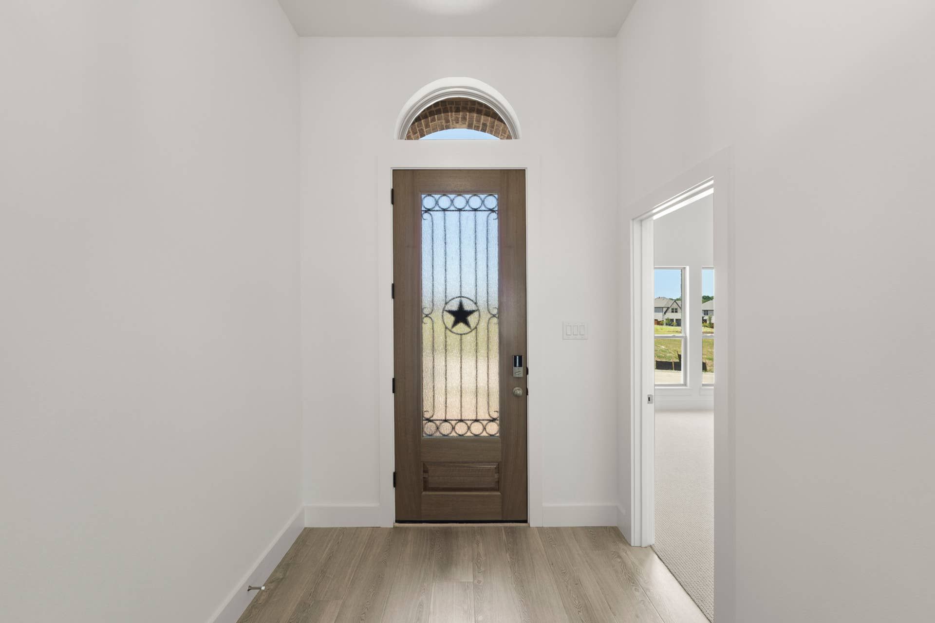 Entryway with wooden door, decorative star design, and arched transom window.