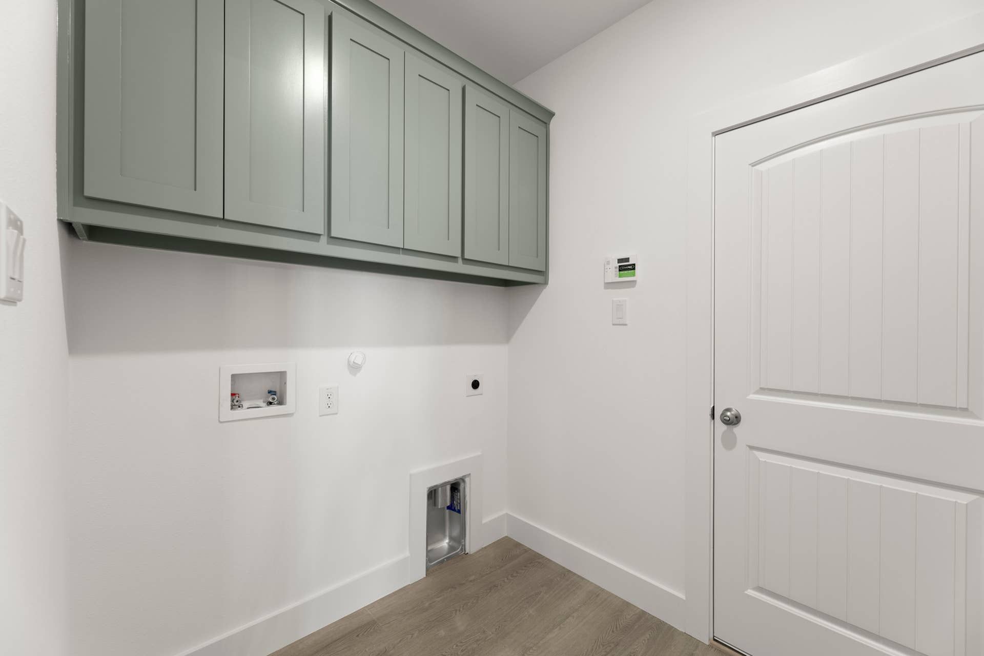 Utility room with green cabinets and white paneled door.
