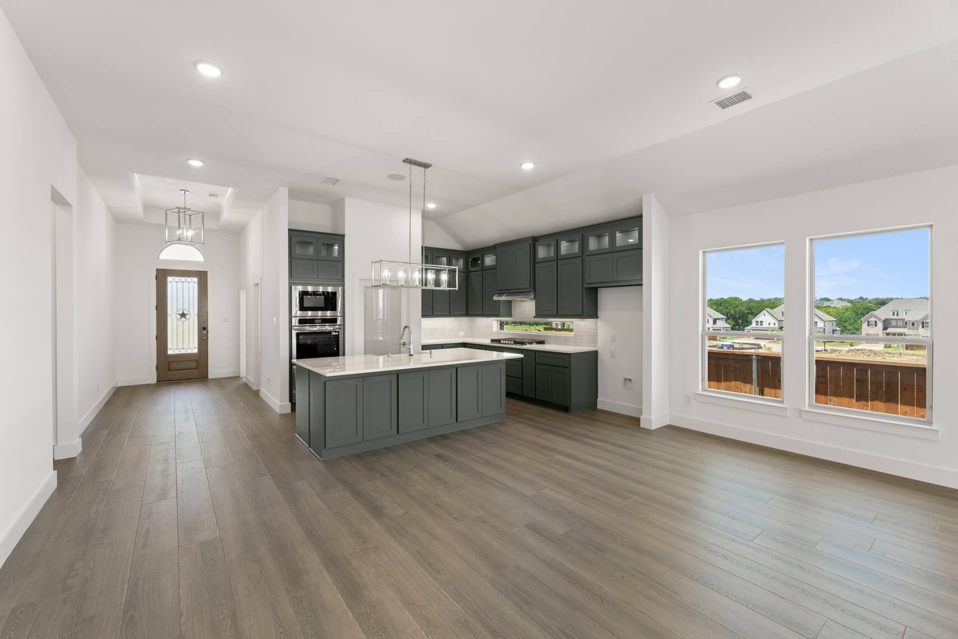 Modern open-concept kitchen and dining area with island and large windows.