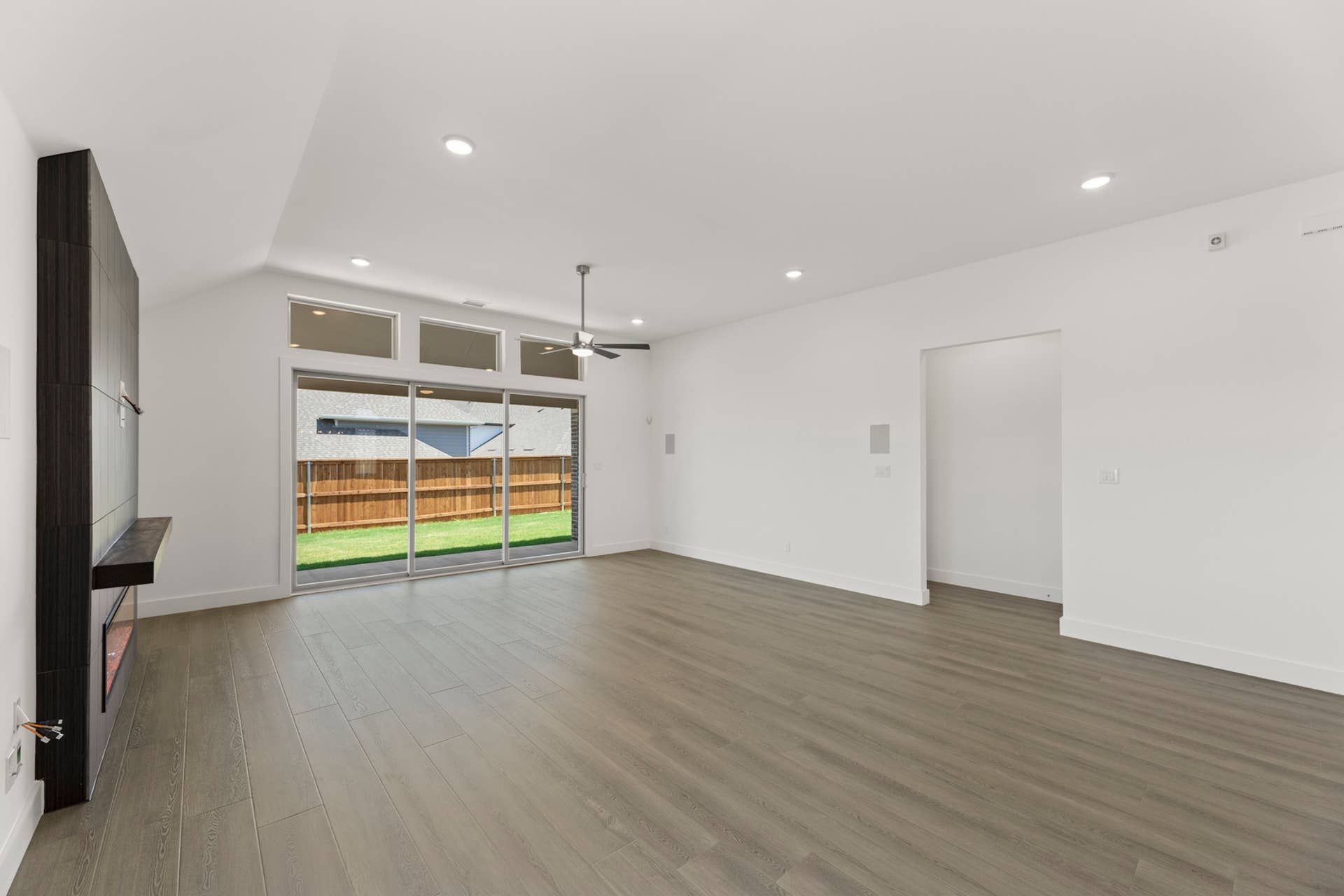 Spacious modern living room with large windows and wooden flooring.
