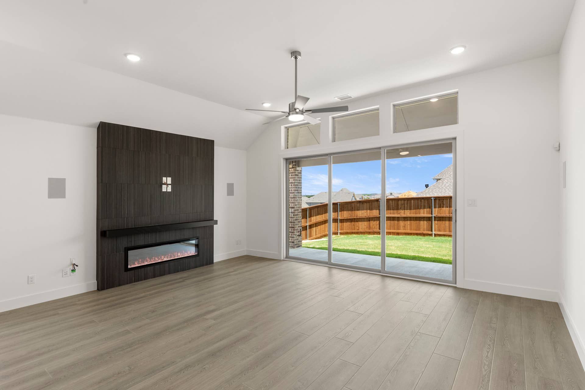 Modern living room with electric fireplace and large sliding glass doors to backyard.