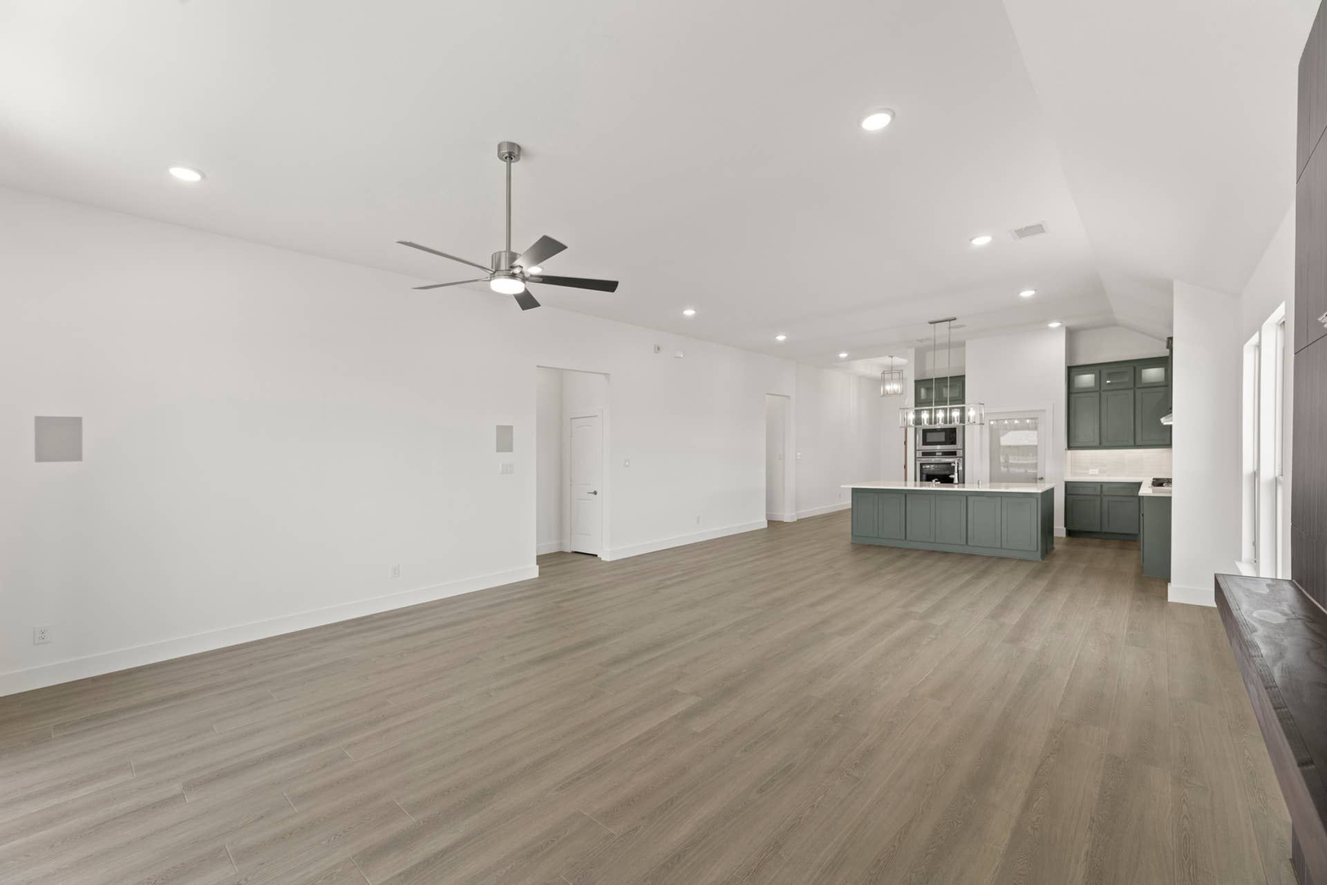 Spacious open-concept living area with modern kitchen and ceiling fan.