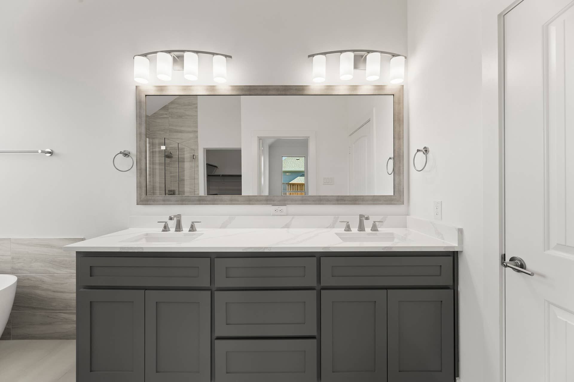 Modern bathroom with dual sinks and large framed mirror.