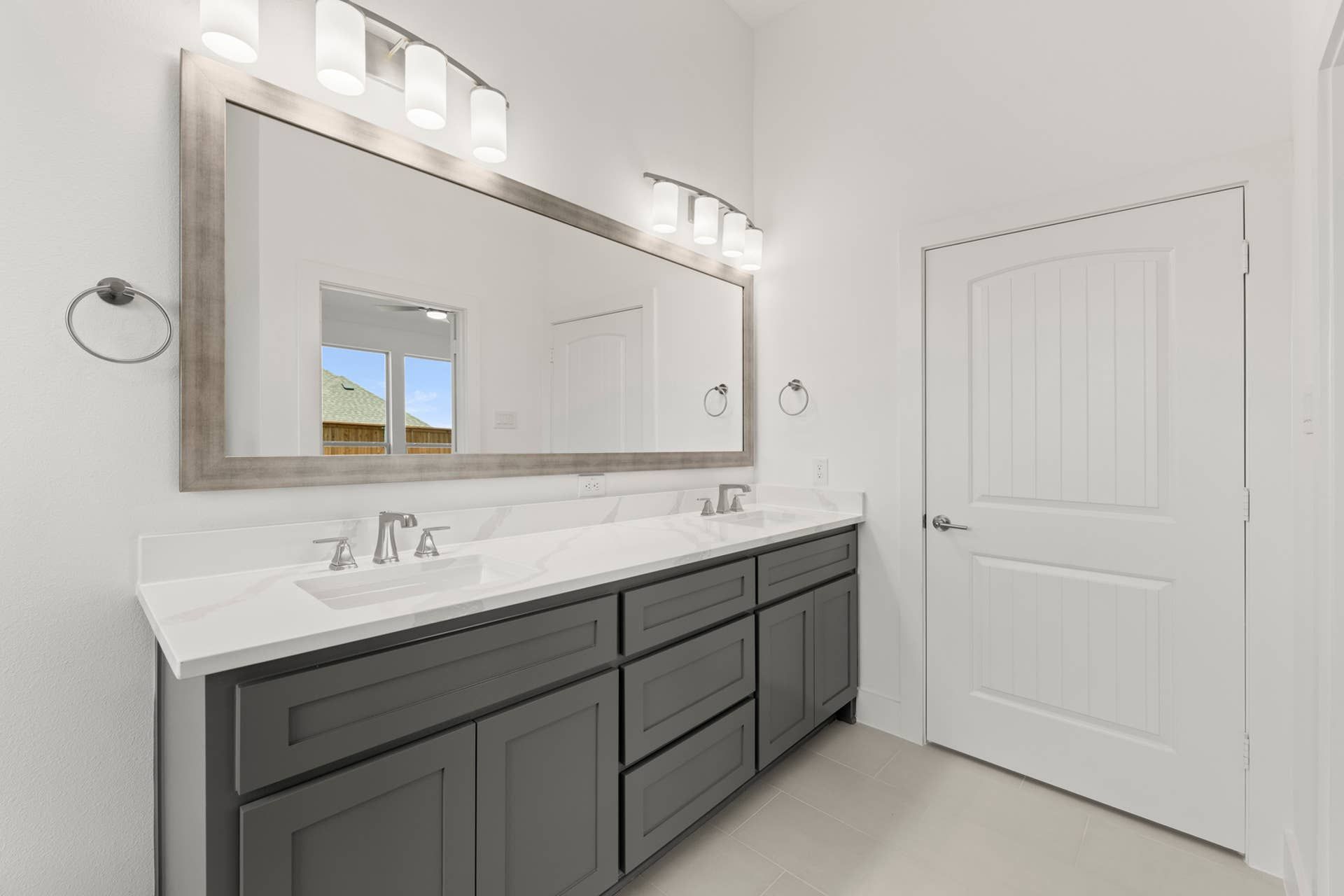 Modern bathroom with dual sinks, large mirror, and sleek cabinetry.