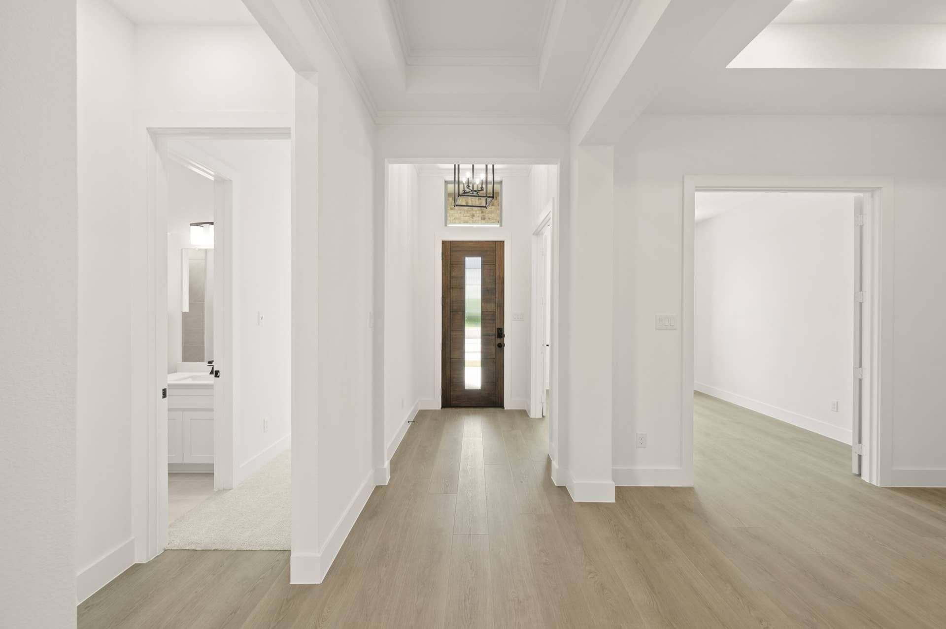 Bright entryway with wooden door and modern chandelier.