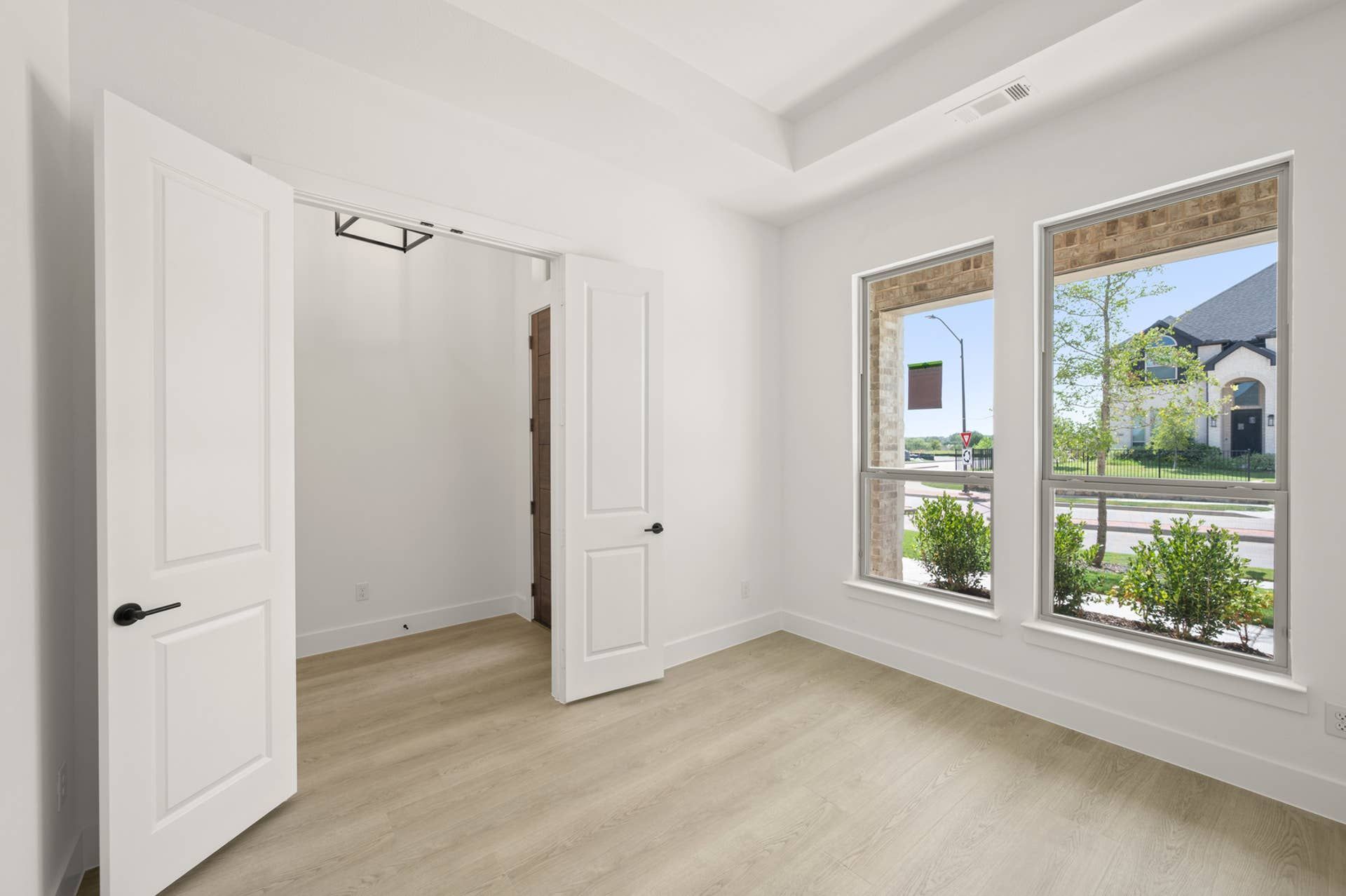 Bright study room with double doors and large windows overlooking the street.