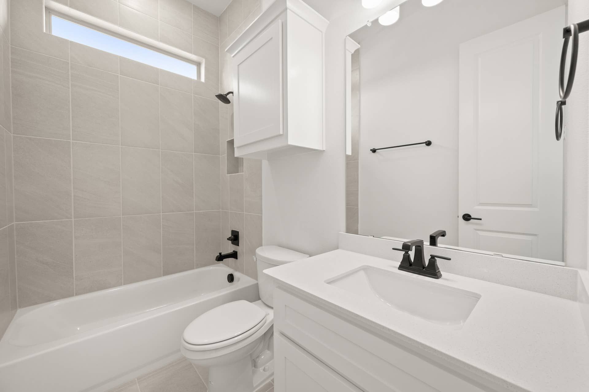 Modern bathroom with white fixtures, tile walls, and sleek black hardware.