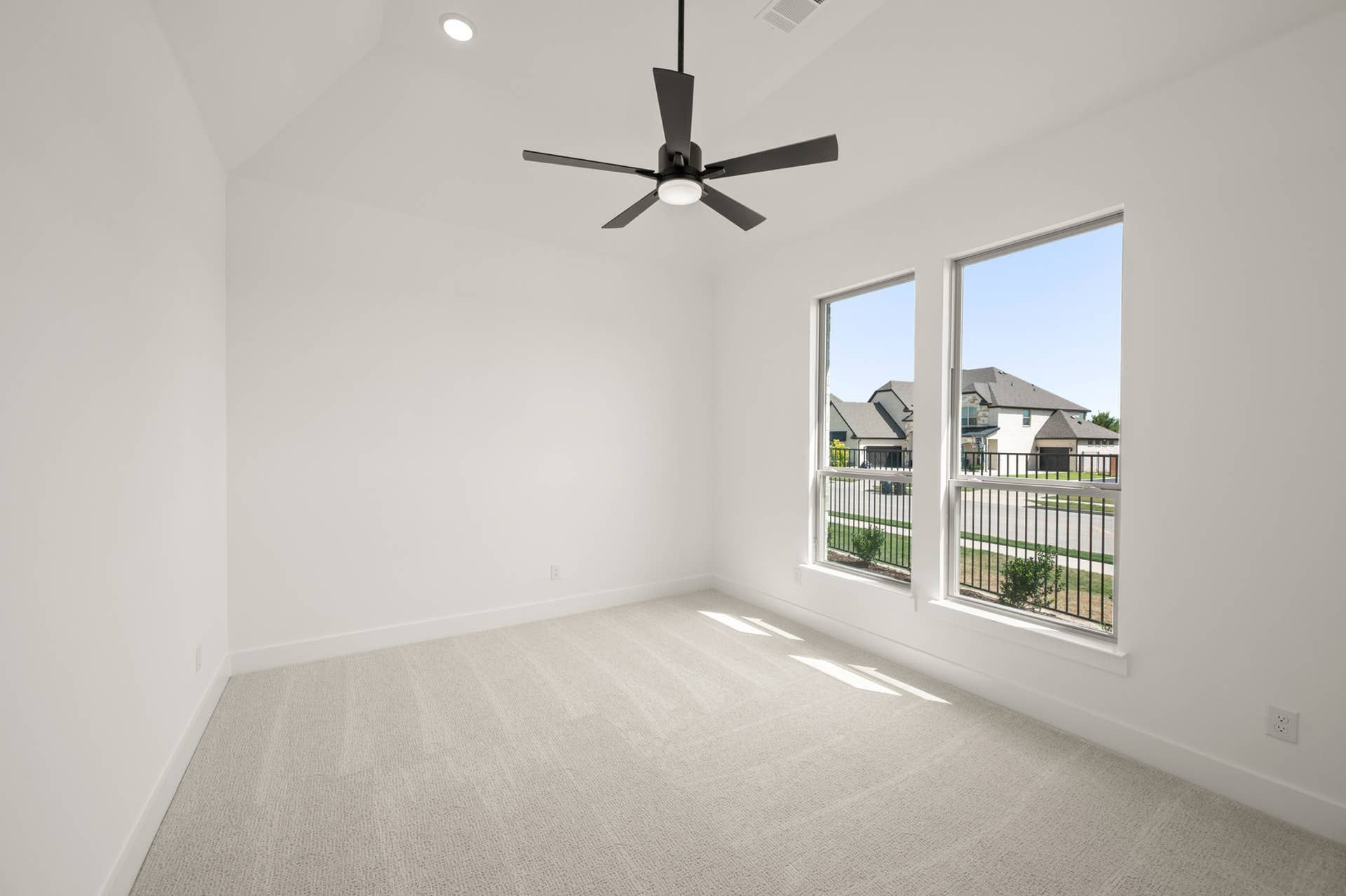 Bright bedroom interior with carpeted floor, large windows, and ceiling fan.