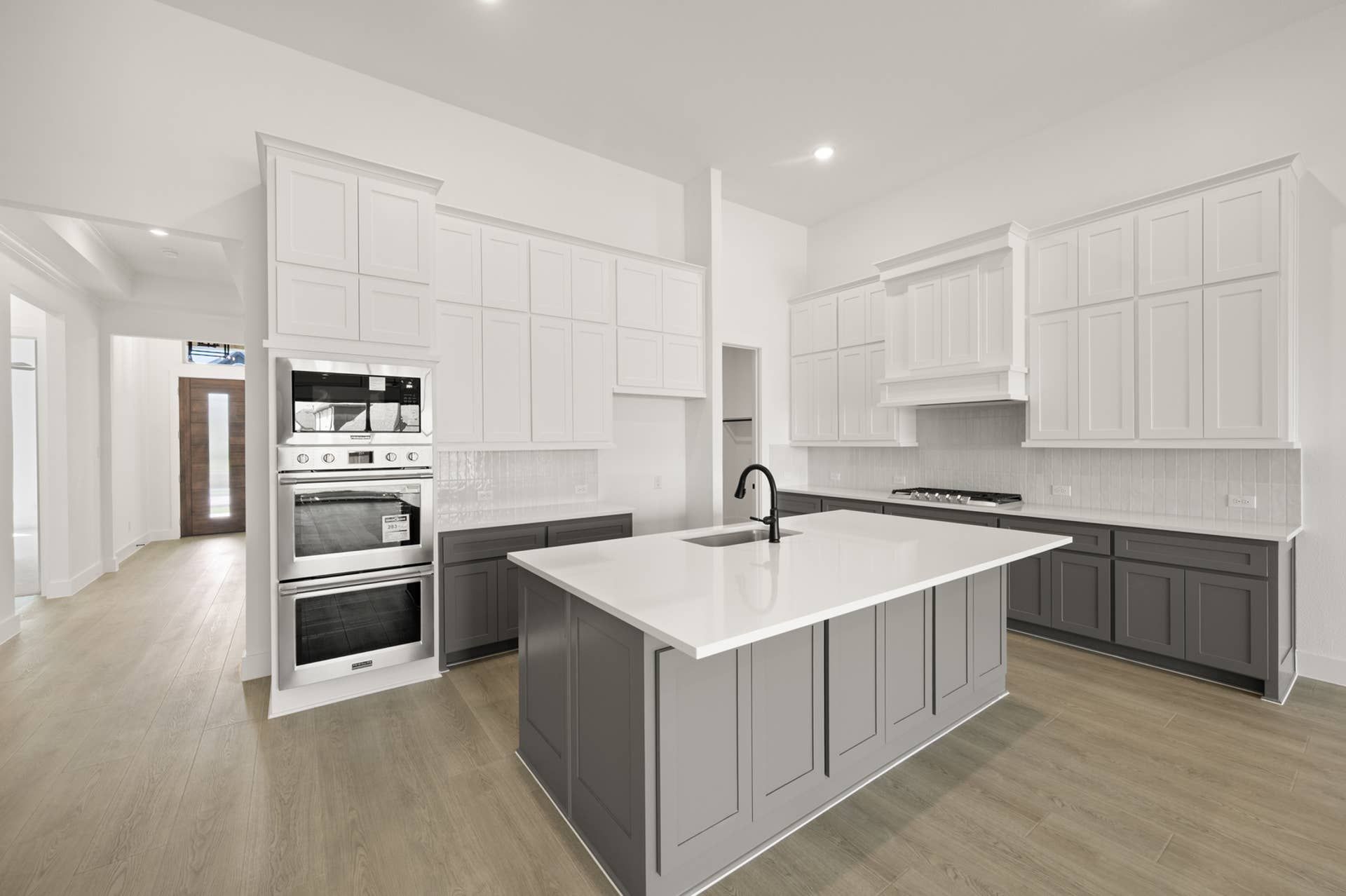 Modern kitchen with white cabinets, large island, and stainless steel appliances.