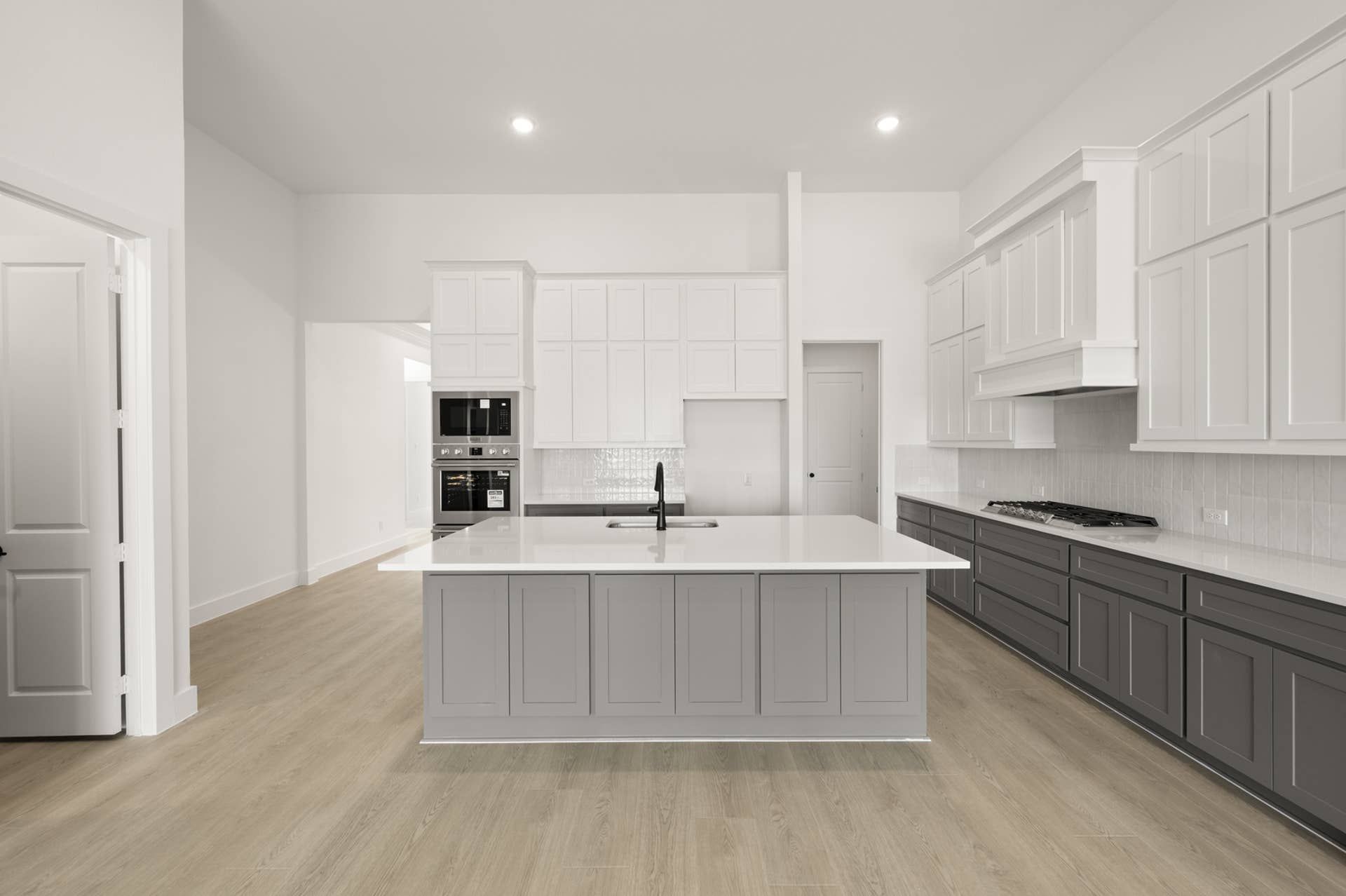 Modern kitchen with island, white cabinetry, and stainless steel appliances.