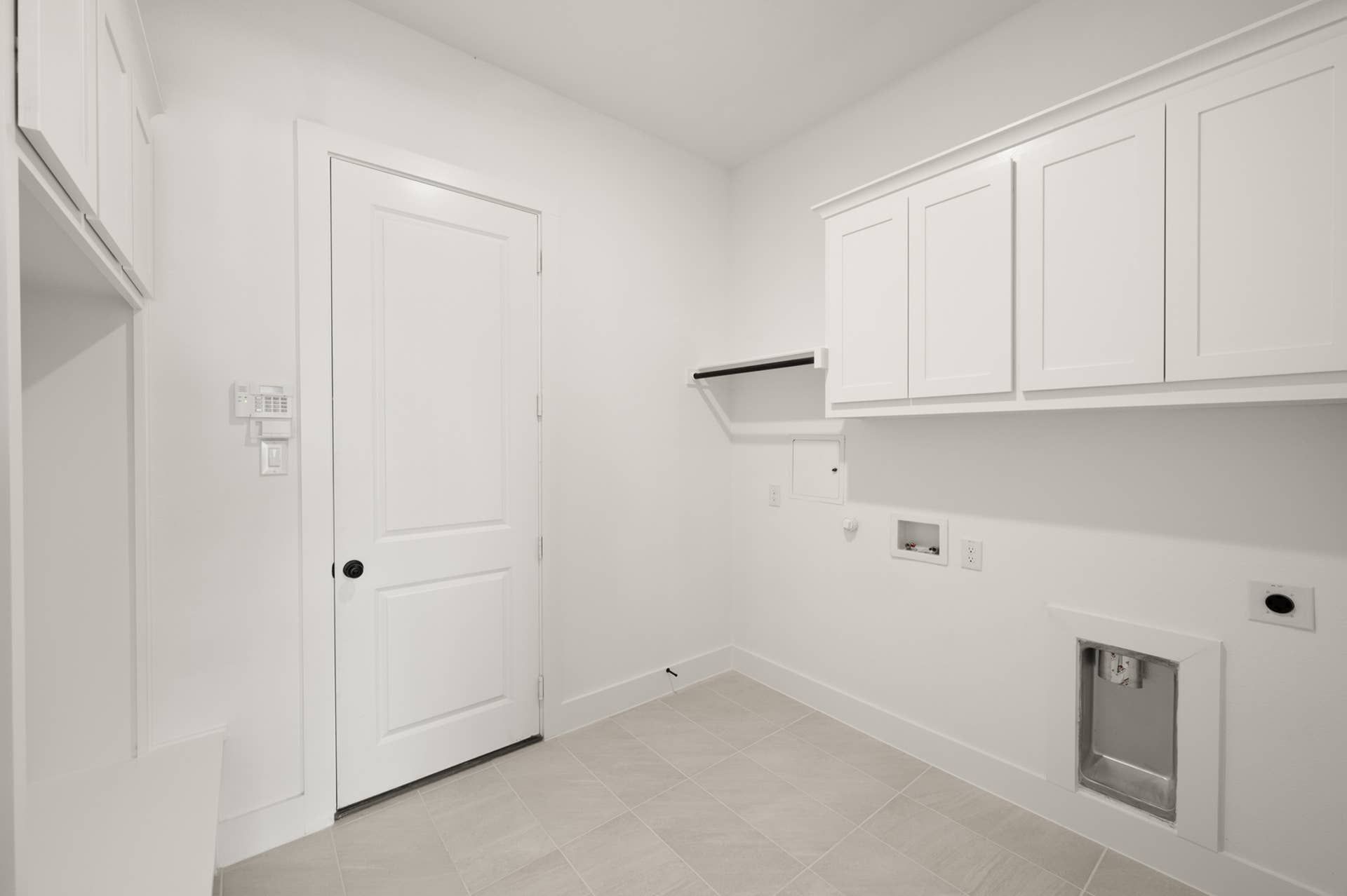 Spacious utility room with white cabinets and tile flooring.