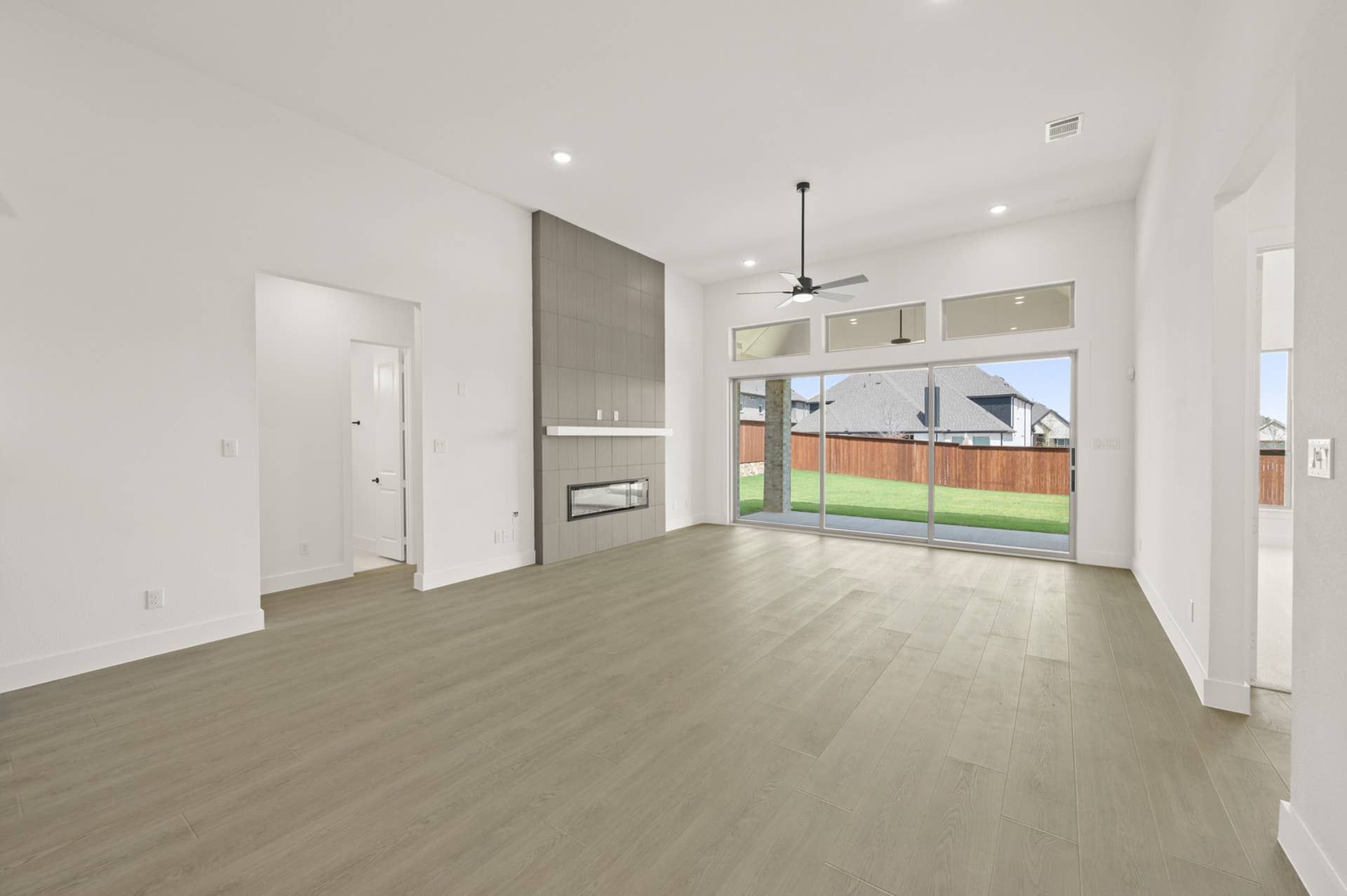 Spacious living room with modern fireplace and large glass doors to backyard.