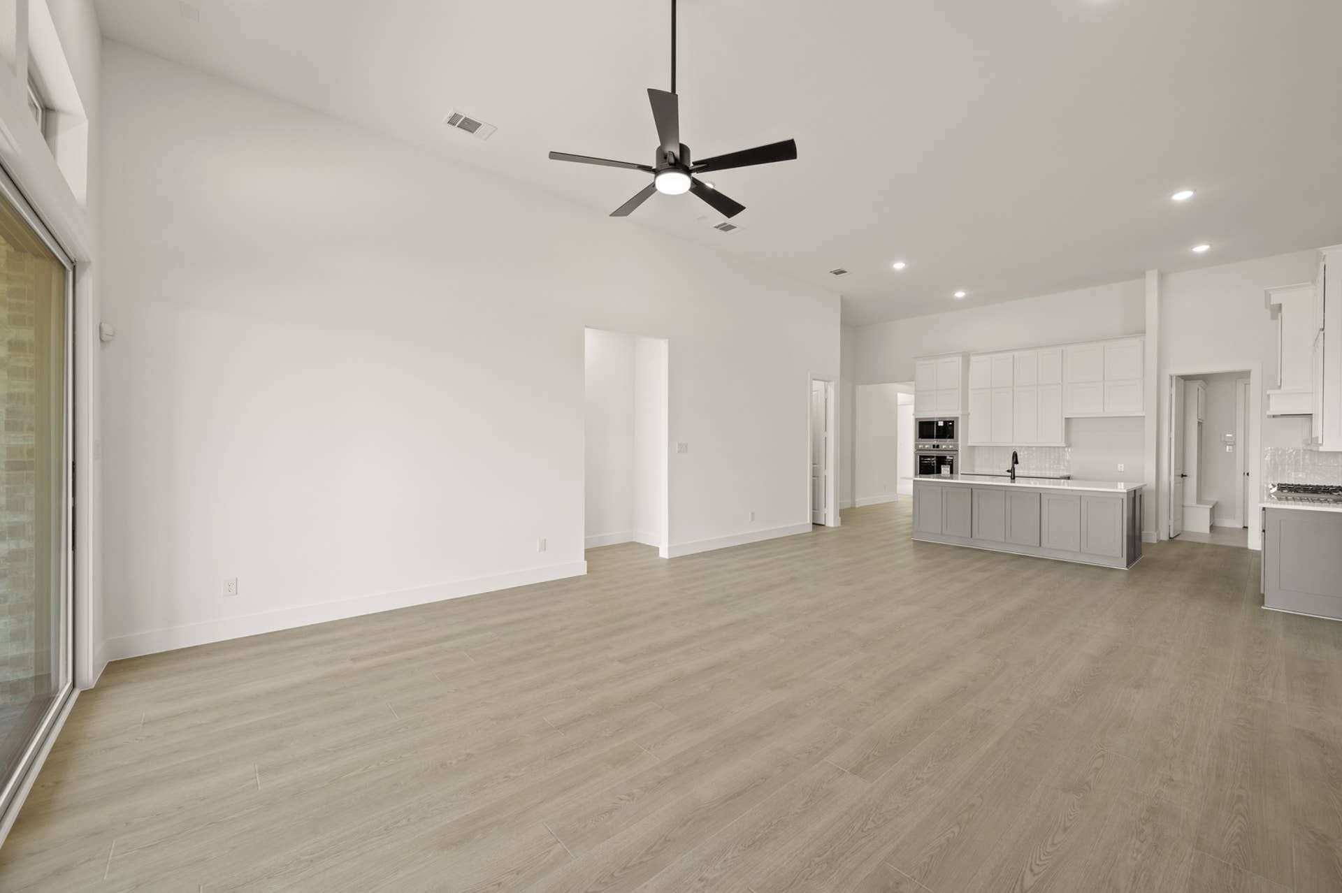 Spacious modern living room with open kitchen and ceiling fan.