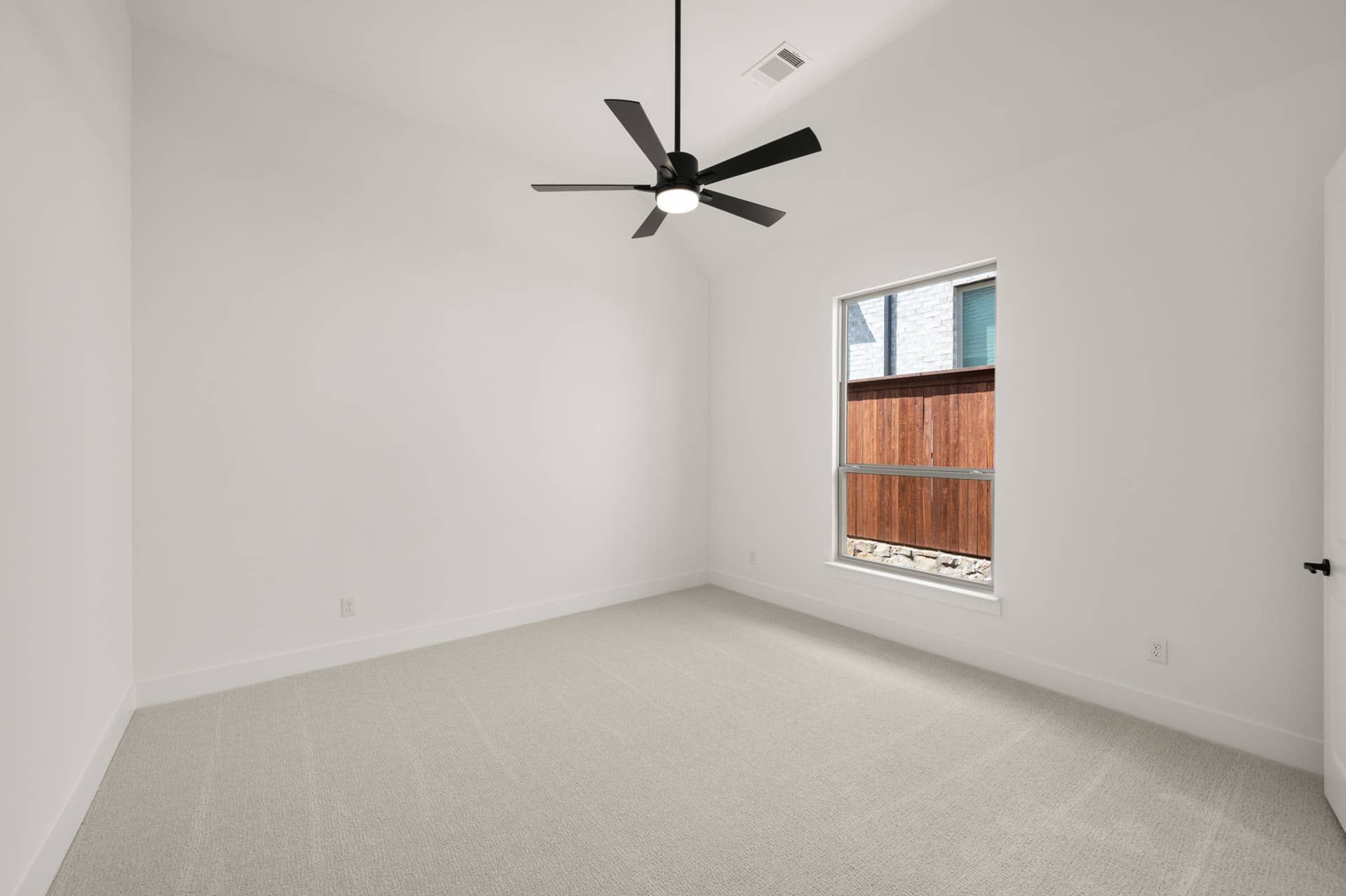 Spacious bedroom with ceiling fan and large window.