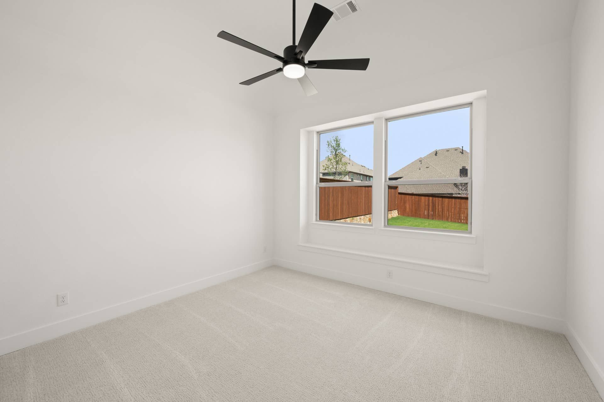 Spacious bedroom with large window and modern ceiling fan.