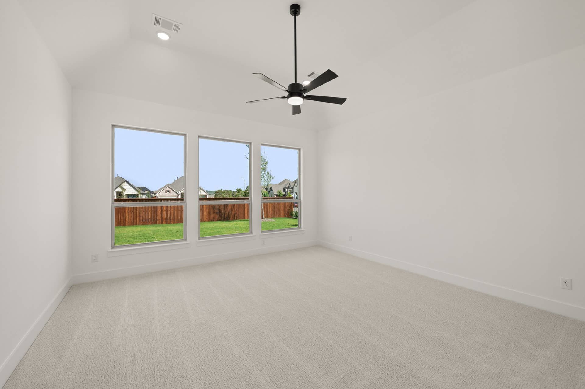 Spacious primary suite with large windows and modern ceiling fan.