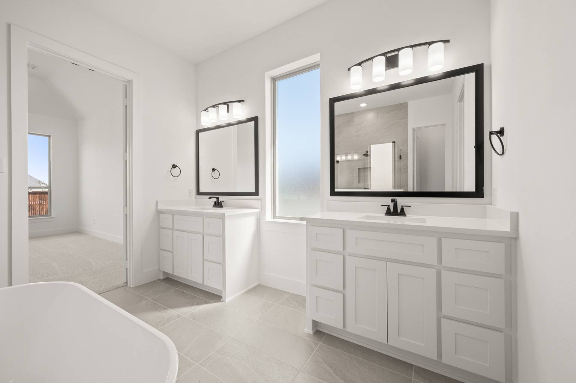 Modern primary suite bathroom with dual vanities and large mirrors.