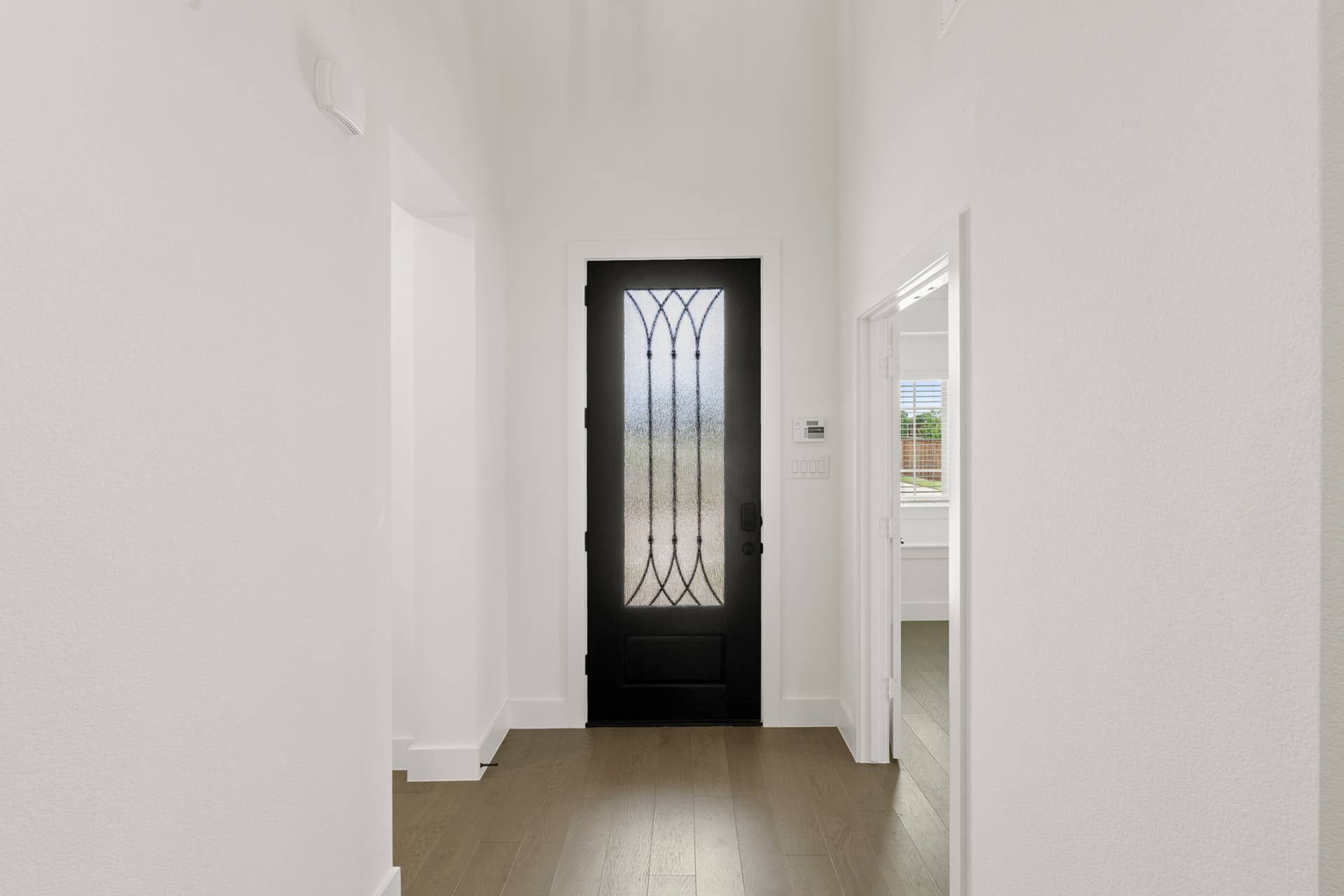 Modern entryway with black door and frosted glass panel.