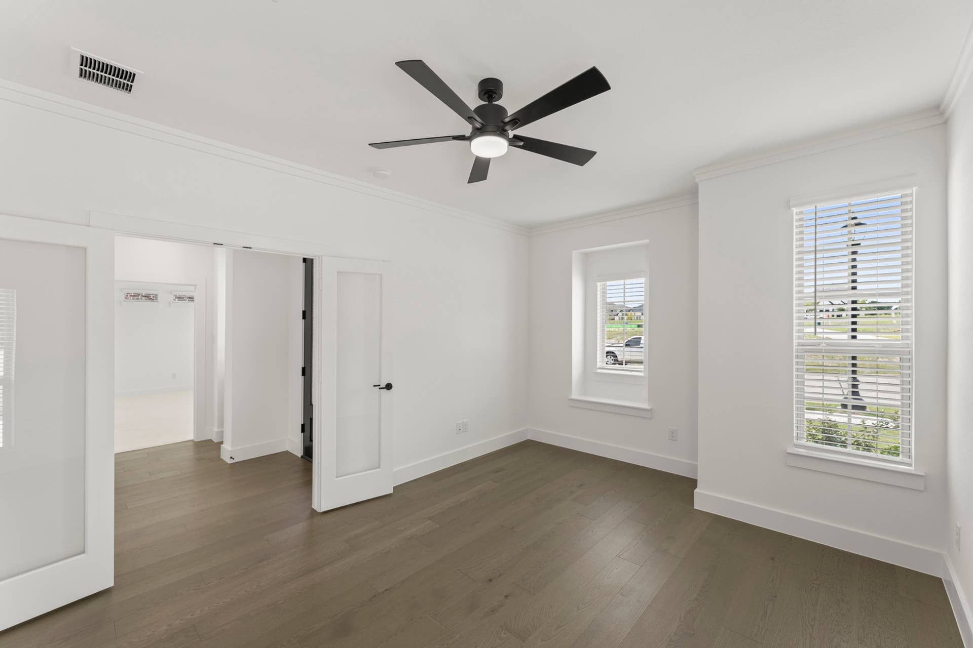 Bright study room with hardwood floors and ceiling fan.