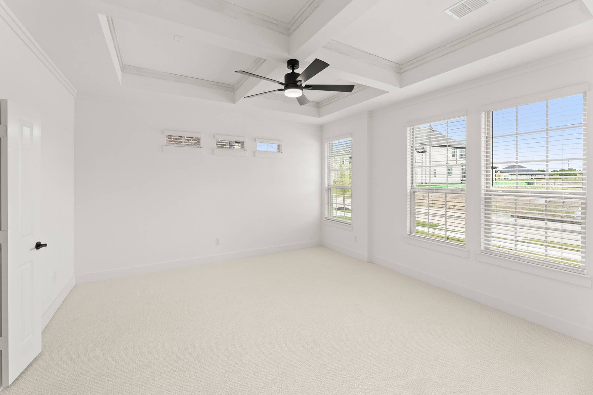 Spacious interior with tray ceiling, large windows, and modern ceiling fan.