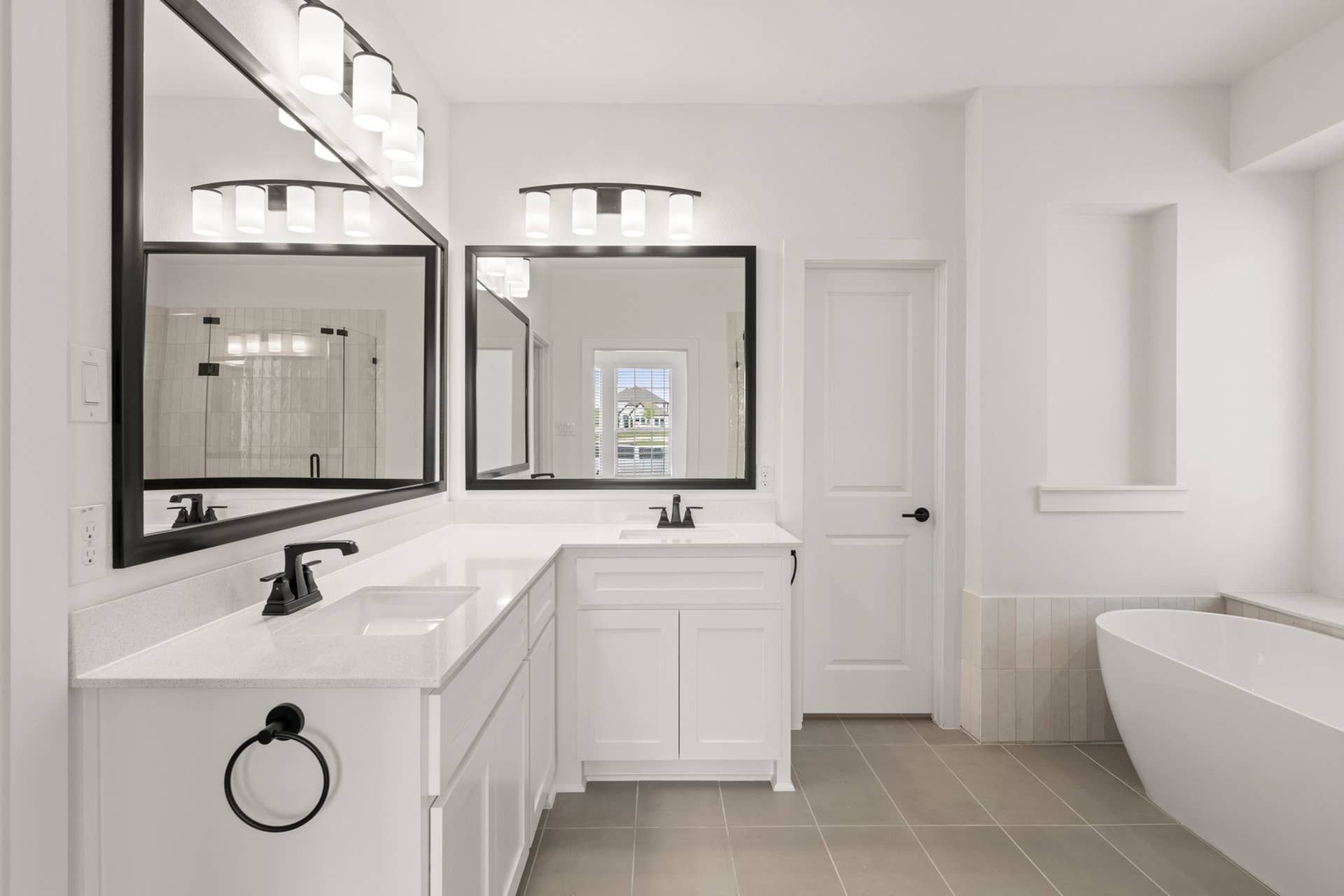 Modern bathroom with dual sinks, large mirrors, and freestanding bathtub.