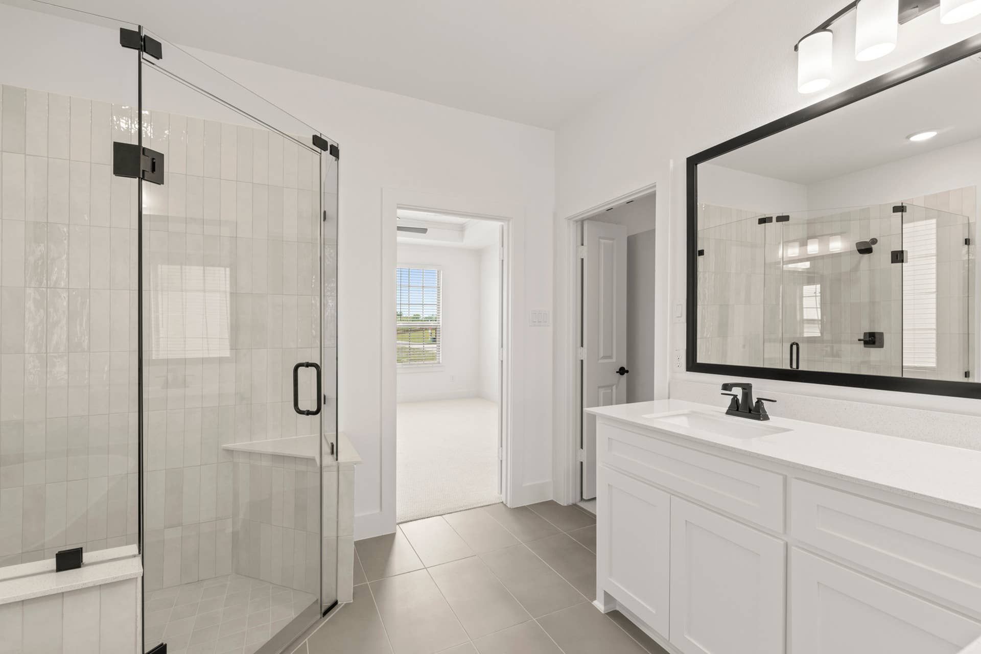 Modern bathroom with glass shower, large mirror, and white vanity.