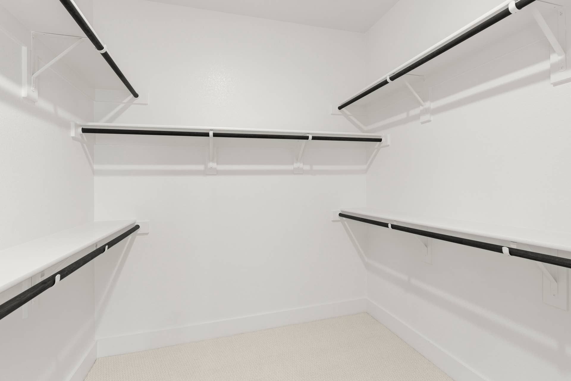 Spacious white walk-in closet with multiple hanging rods and shelving.