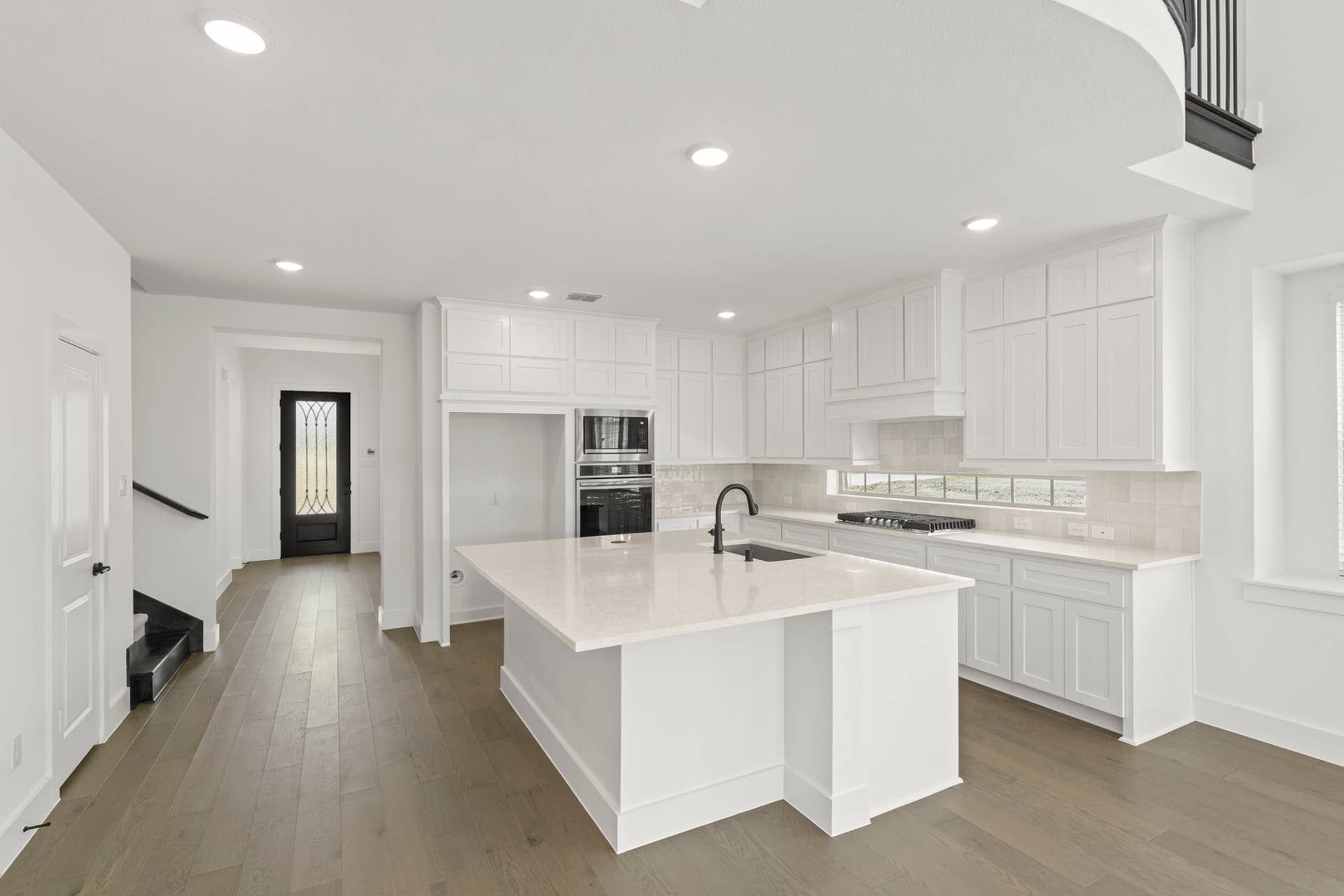Modern kitchen with white cabinetry, island, and hardwood flooring.