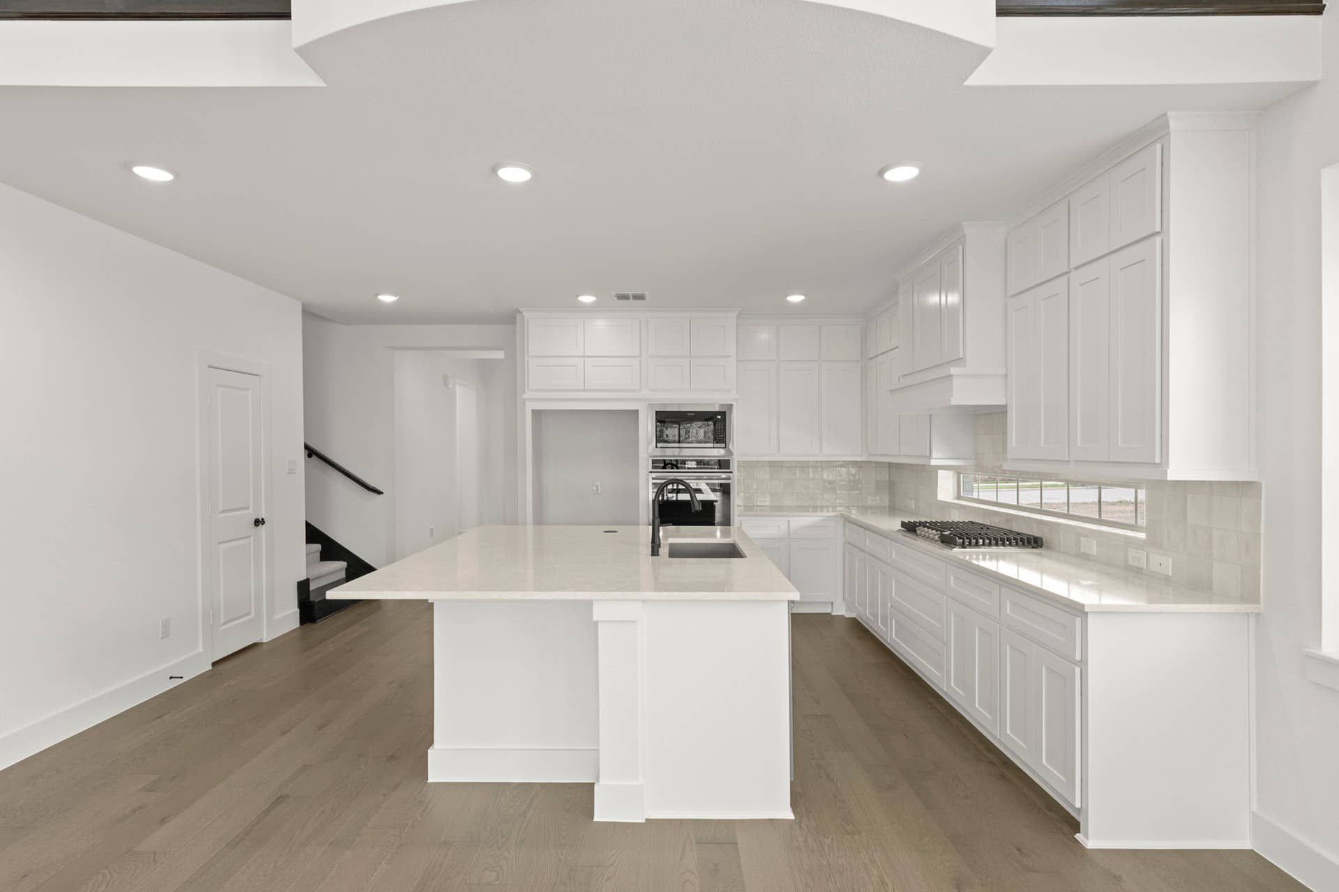 Modern kitchen with white cabinetry, large island, and wood flooring.