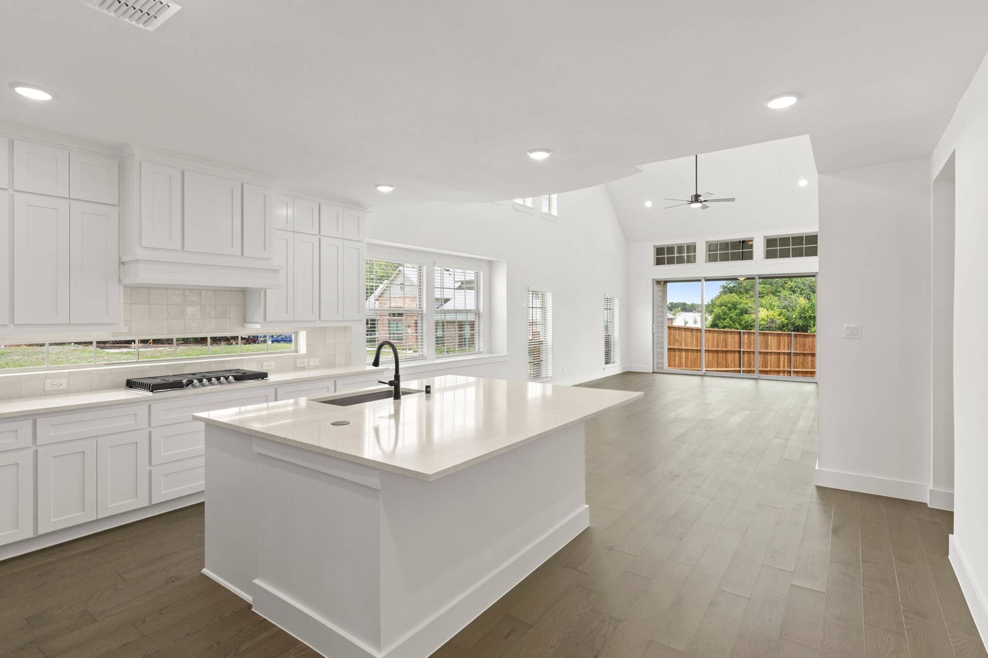 Spacious modern kitchen with white cabinetry and large island, overlooking open living area.