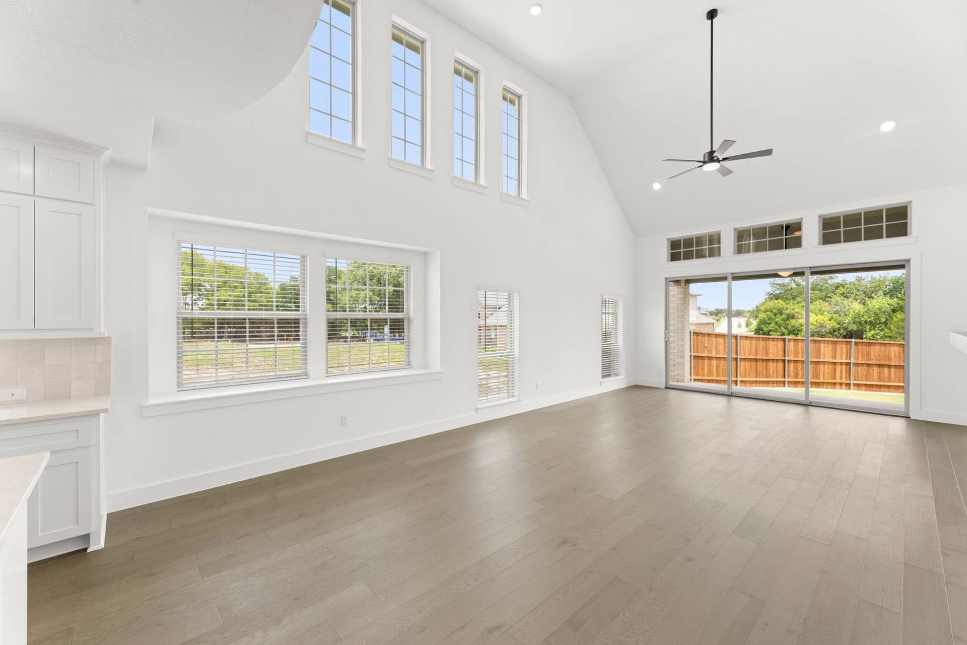Spacious dining room with high ceilings, large windows, and sliding glass door to backyard.
