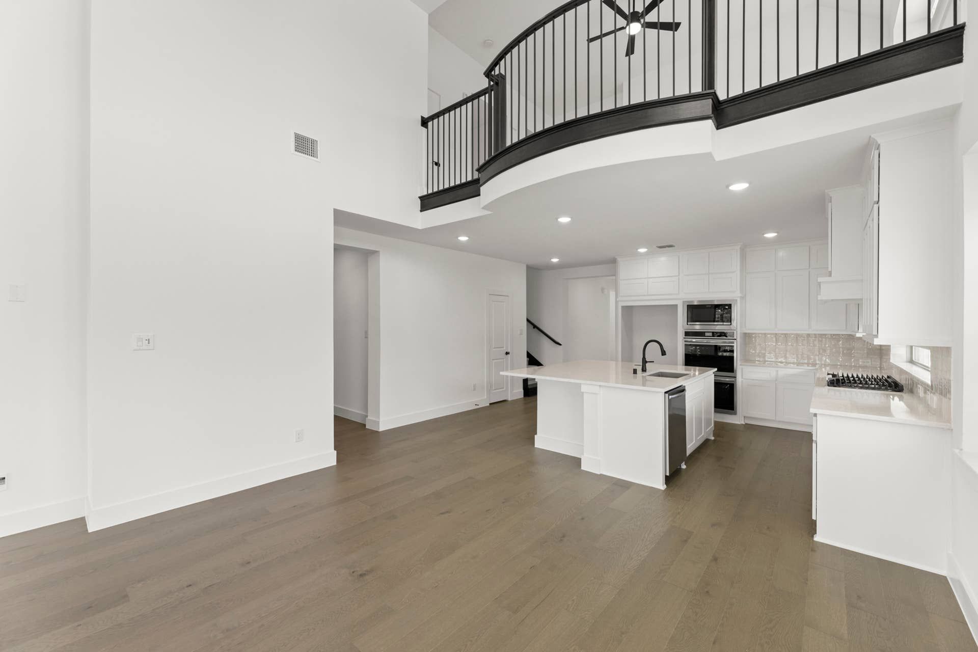 Modern kitchen interior with island, high ceilings, and open balcony.
