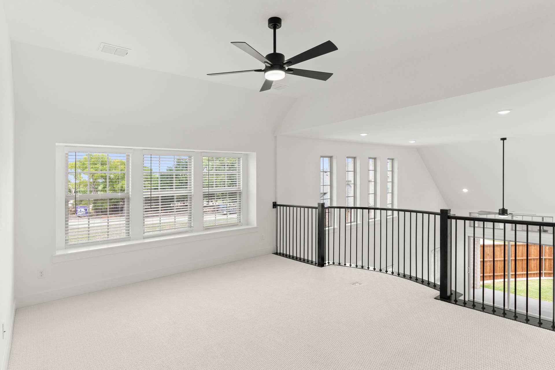Bright loft area with modern ceiling fan and large windows.