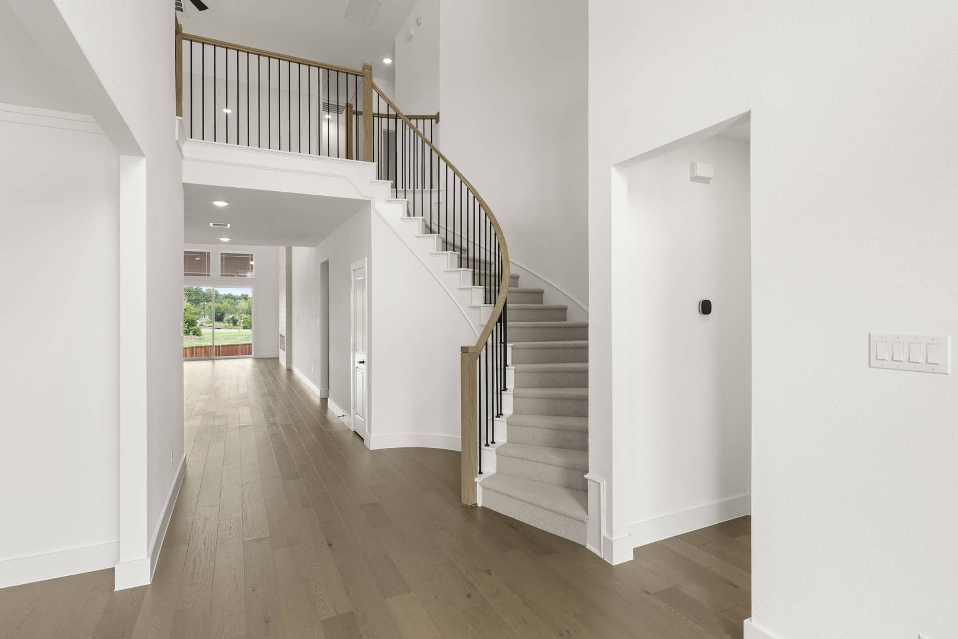 Elegant entryway with curved staircase and hardwood floors in modern home interior.