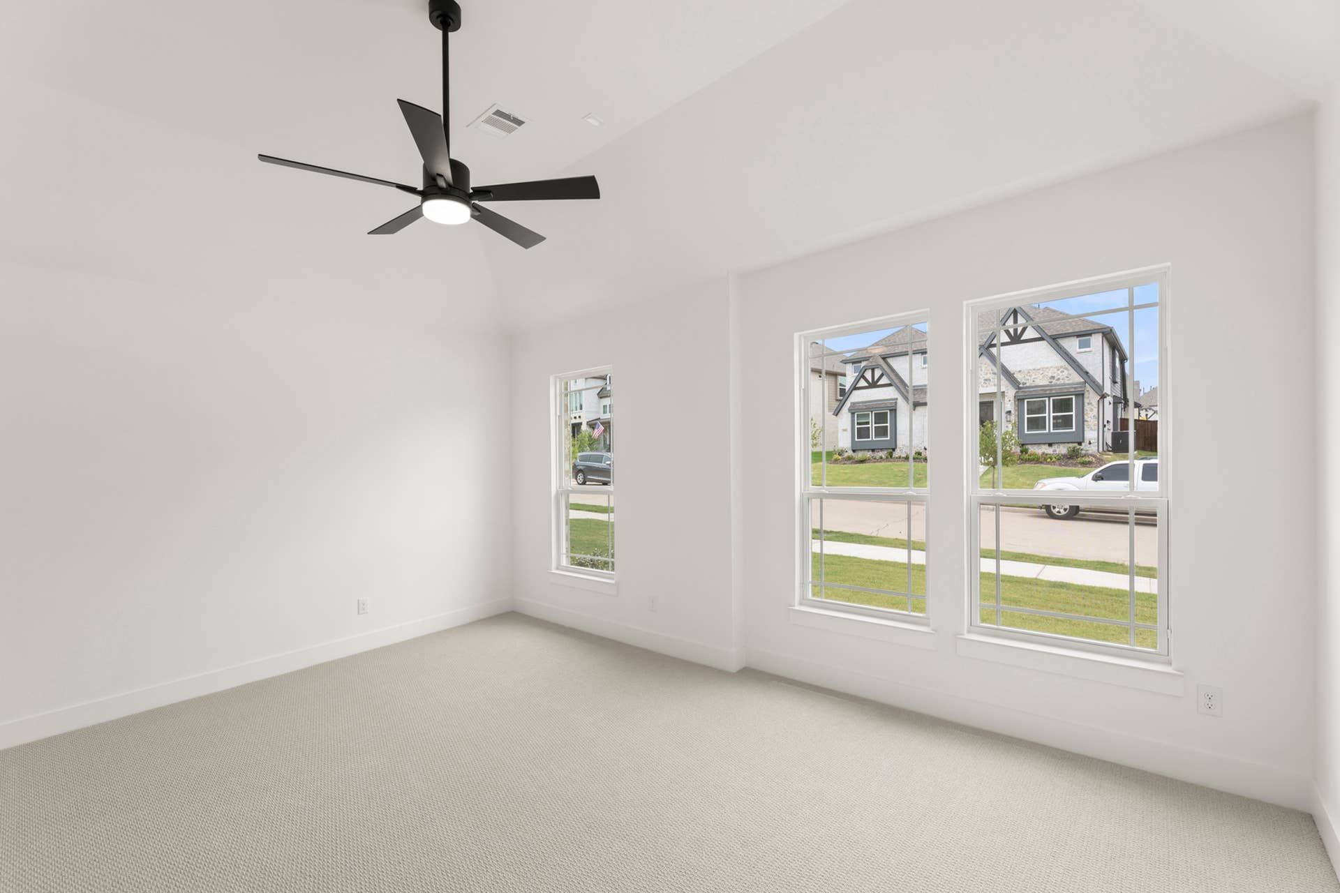 Spacious primary bedroom with large windows and modern ceiling fan.