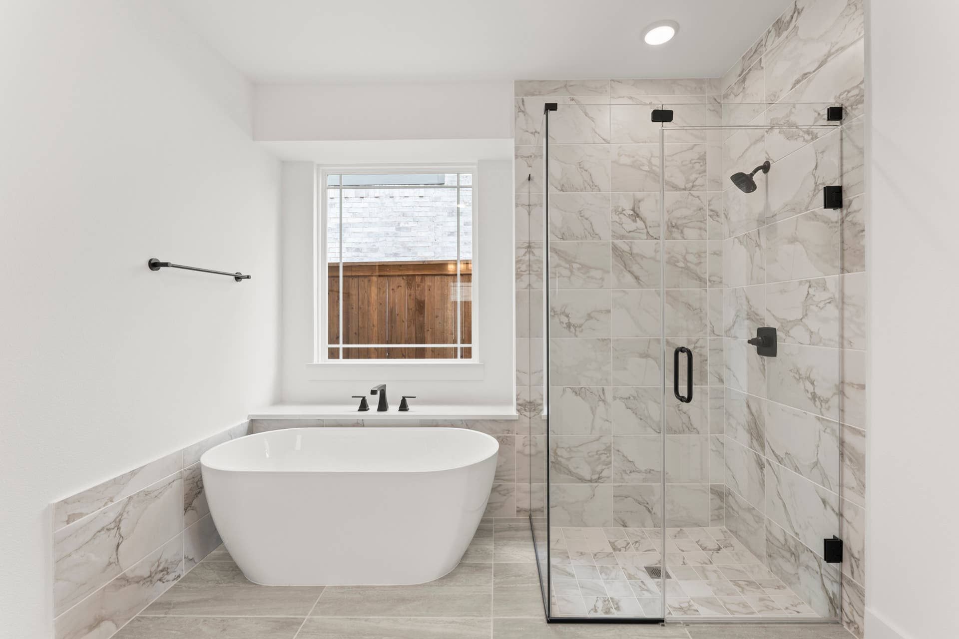 Modern bathroom with freestanding tub and glass-enclosed marble shower.