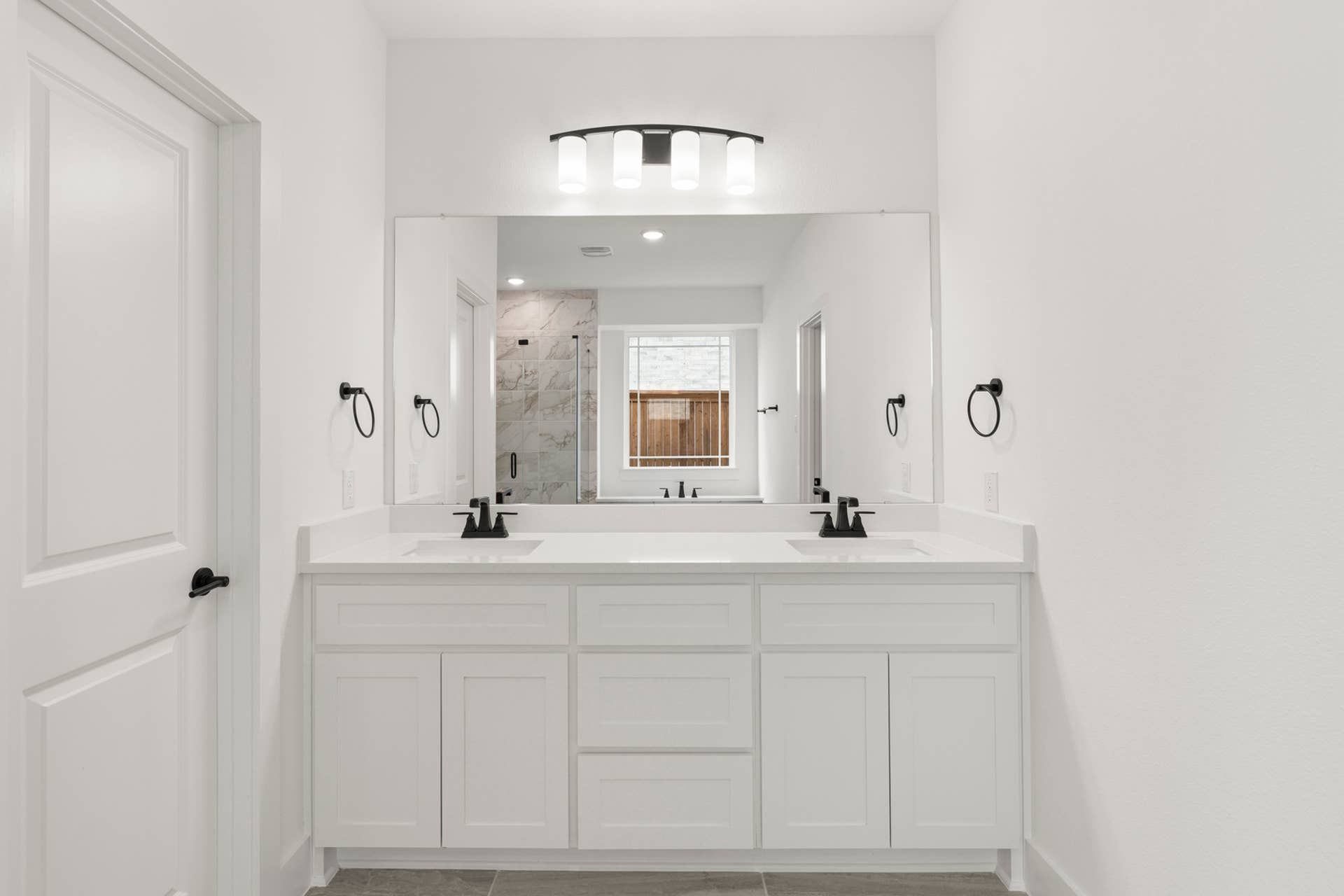 Modern bathroom with dual sinks, large mirror, and glass-enclosed shower.