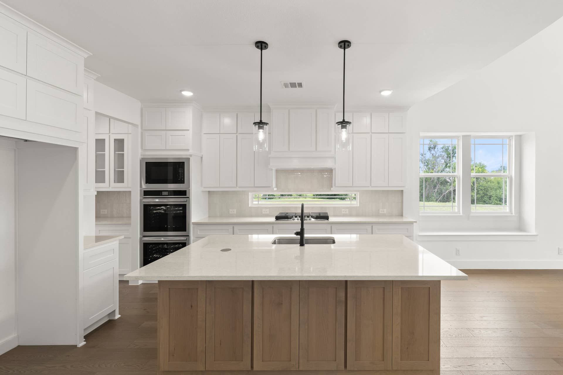 Modern kitchen with white cabinetry, island, and pendant lighting.
