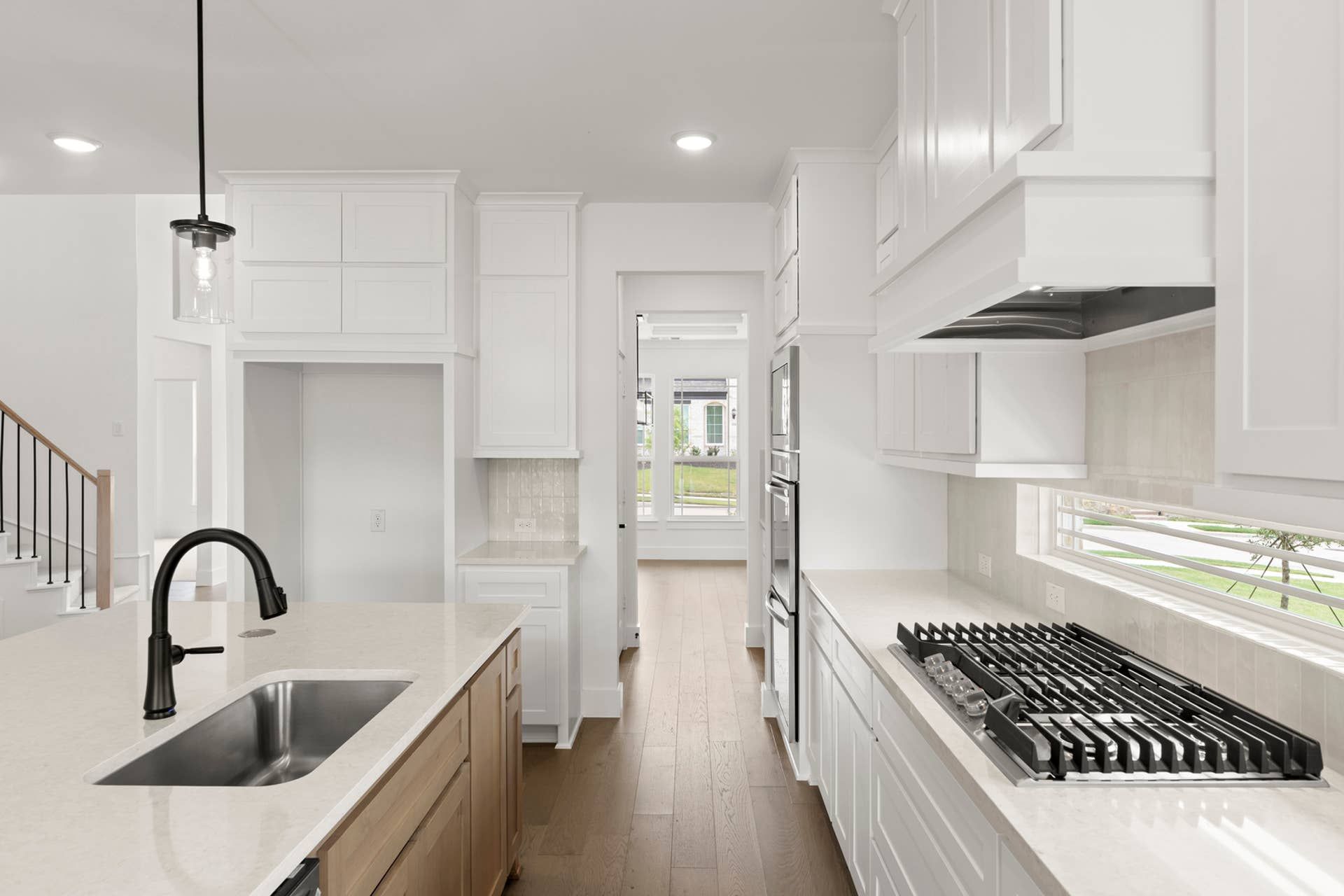 Modern kitchen with white cabinetry, island sink, and stainless steel appliances.