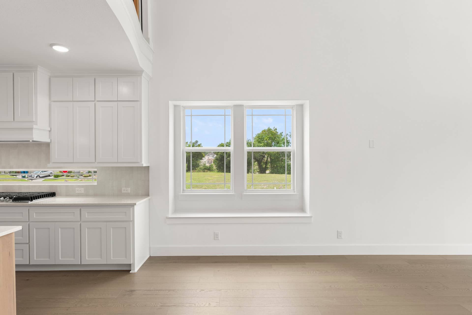 Bright kitchen nook with white cabinetry and large window view.