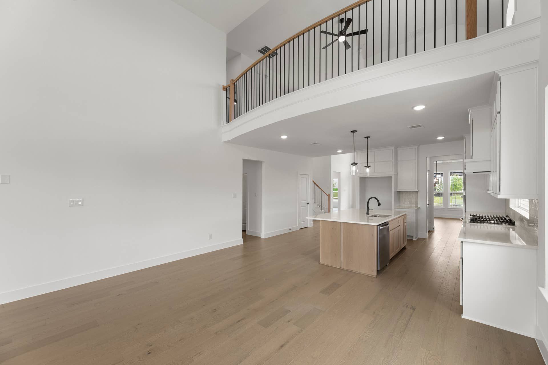 Spacious modern kitchen with island, vaulted ceiling, and mezzanine railing.