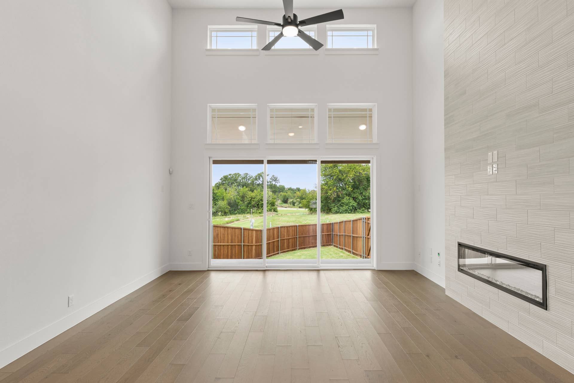 Spacious living room with large windows, modern fireplace, and wood flooring.