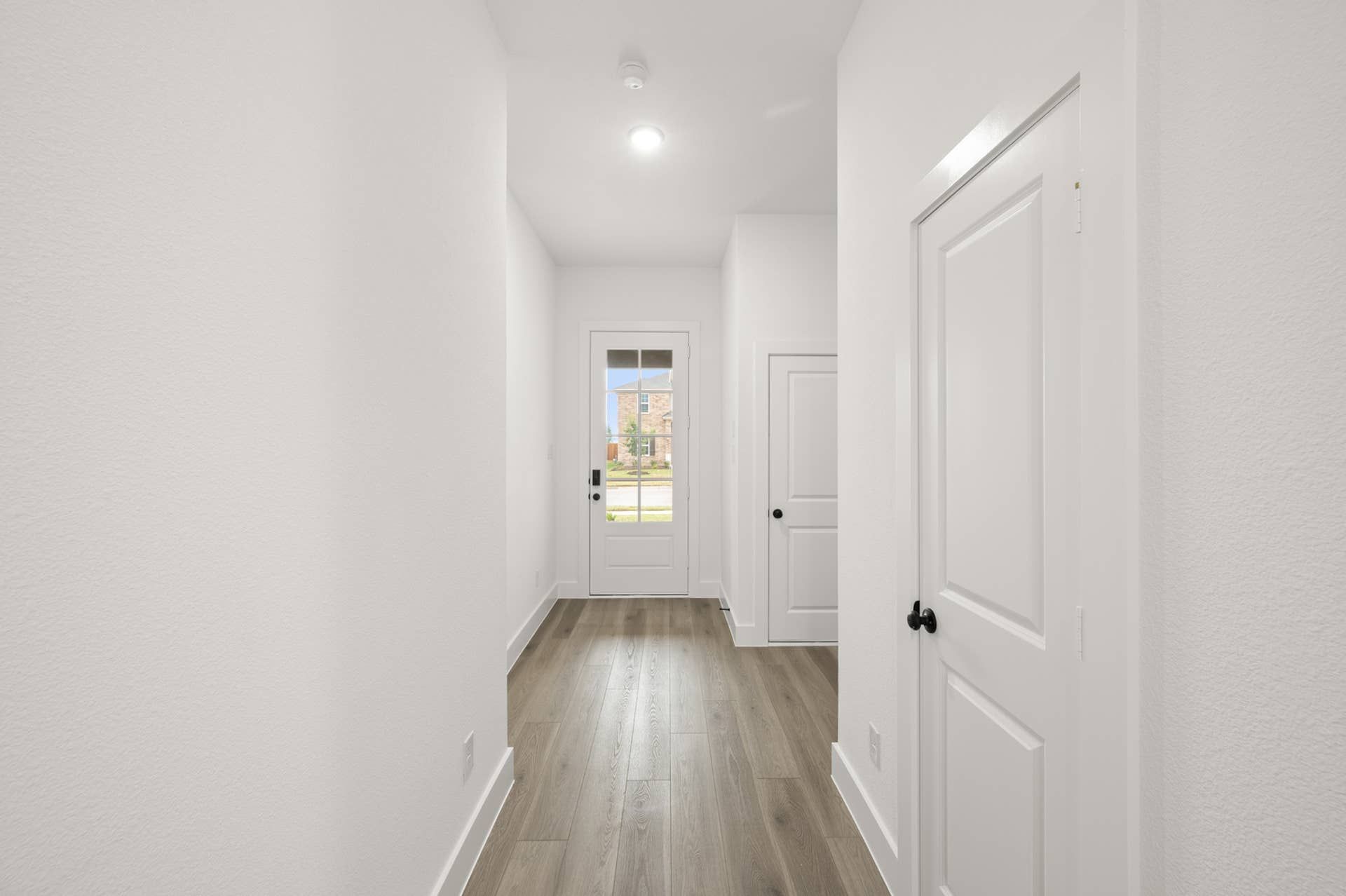 Bright entryway with wood flooring and a glass front door.