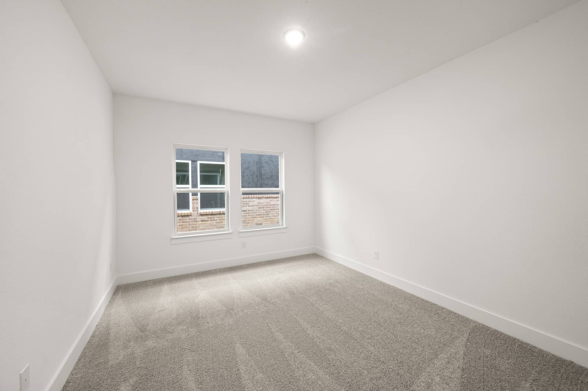 Spacious bedroom with carpet and double windows providing natural light.
