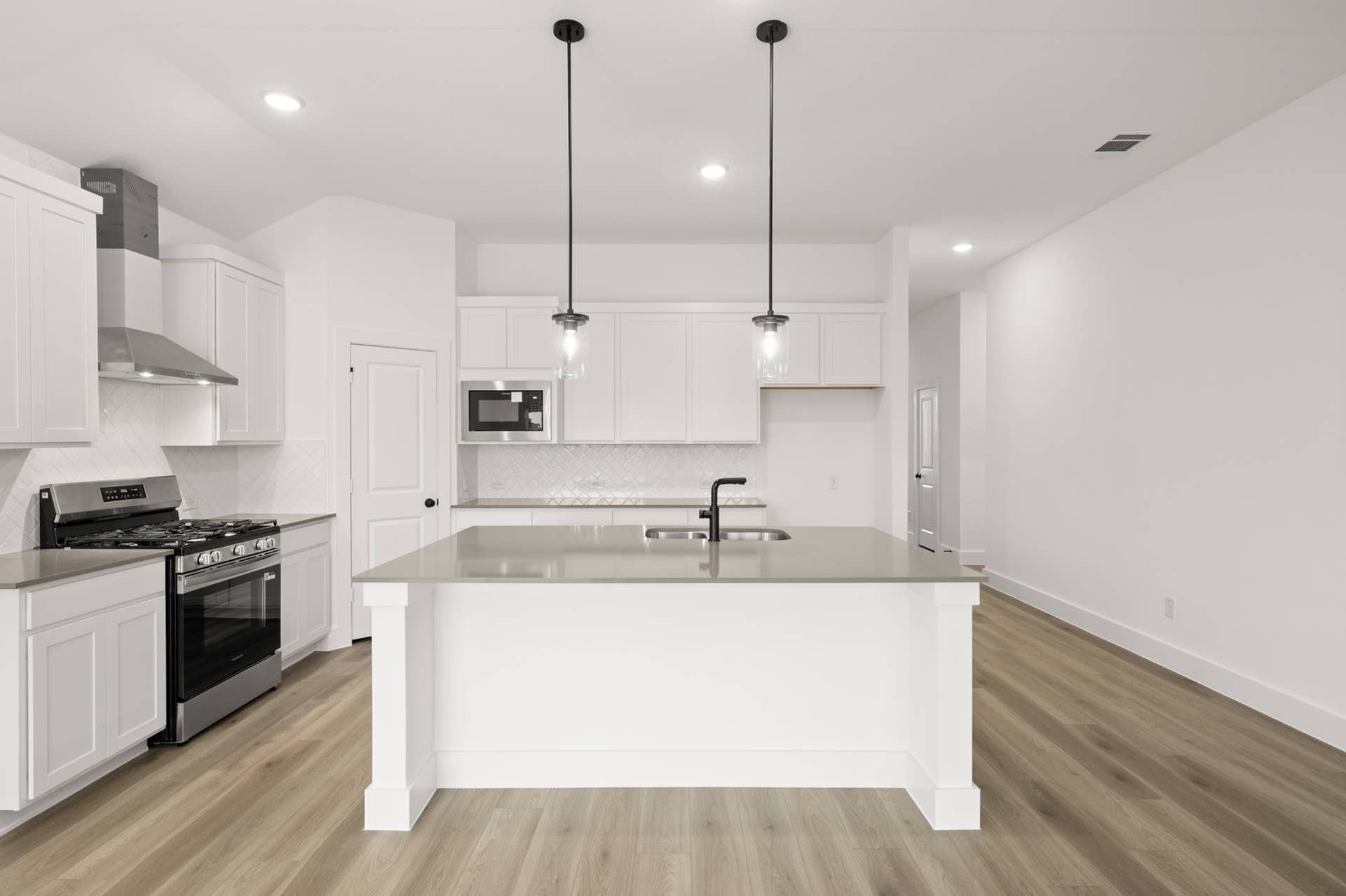 Modern kitchen with white cabinetry, island, and stainless steel appliances.