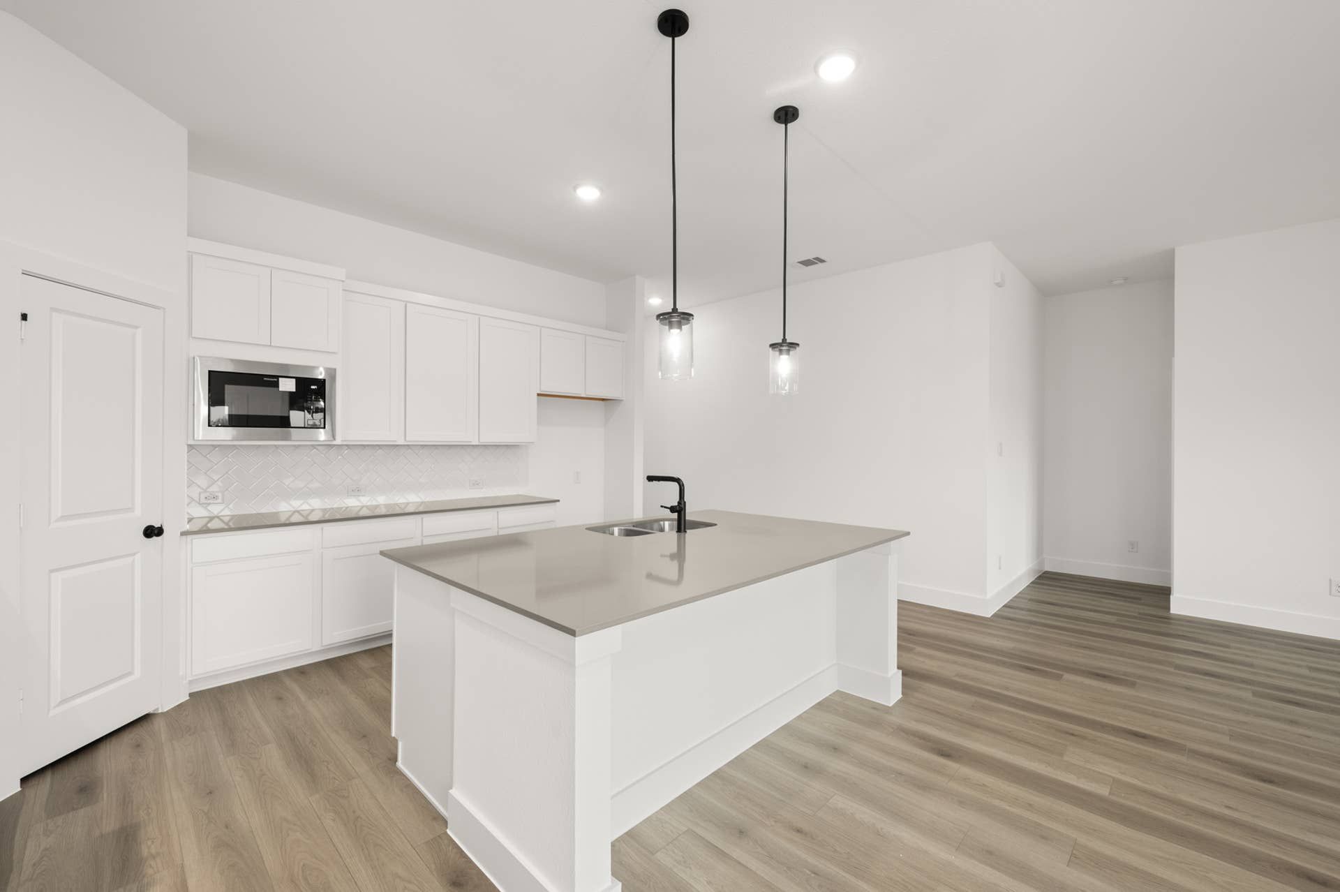 Modern kitchen with white cabinets, island, and pendant lighting.