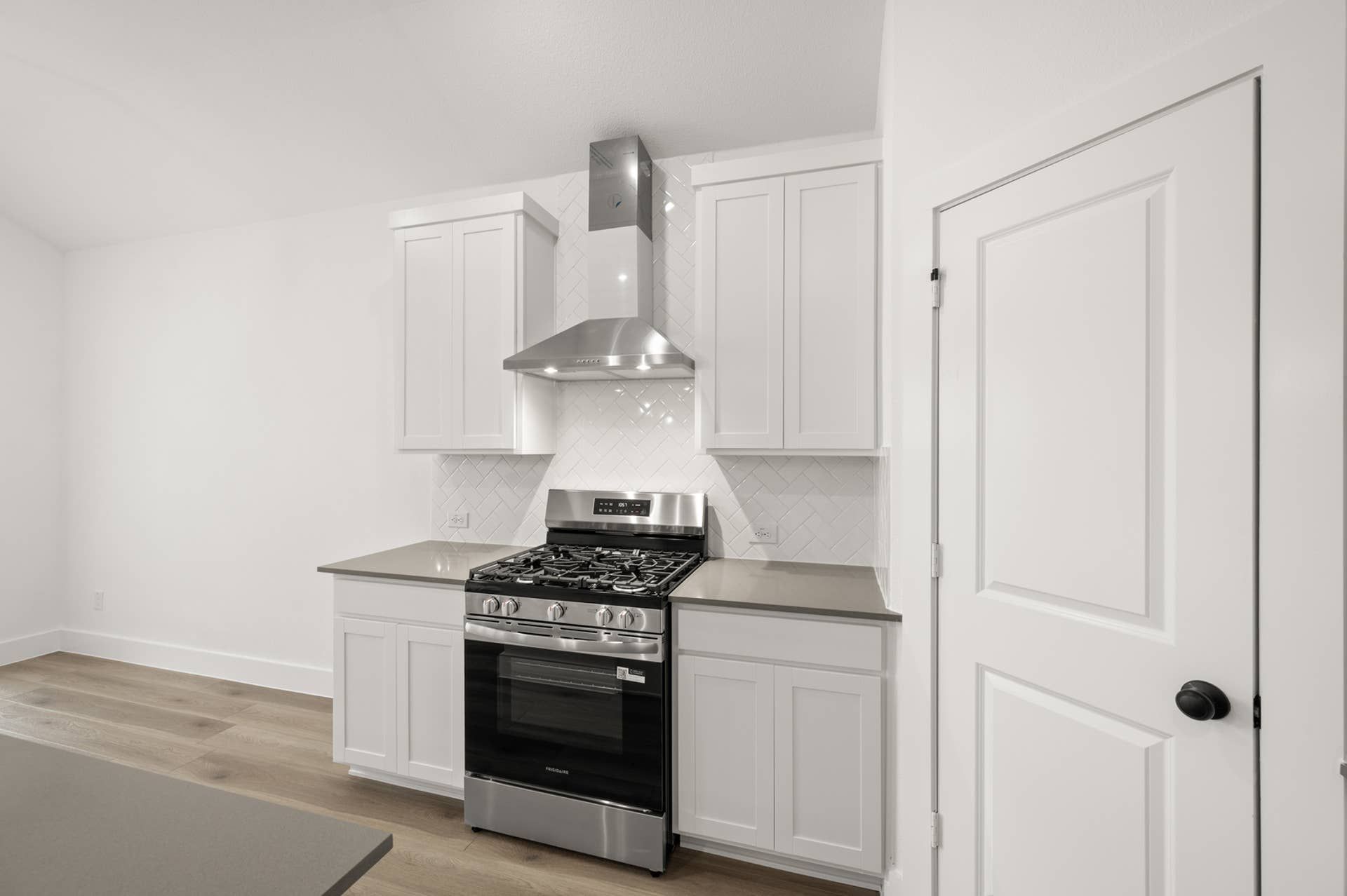 Modern kitchen with stainless steel stove and white cabinetry.