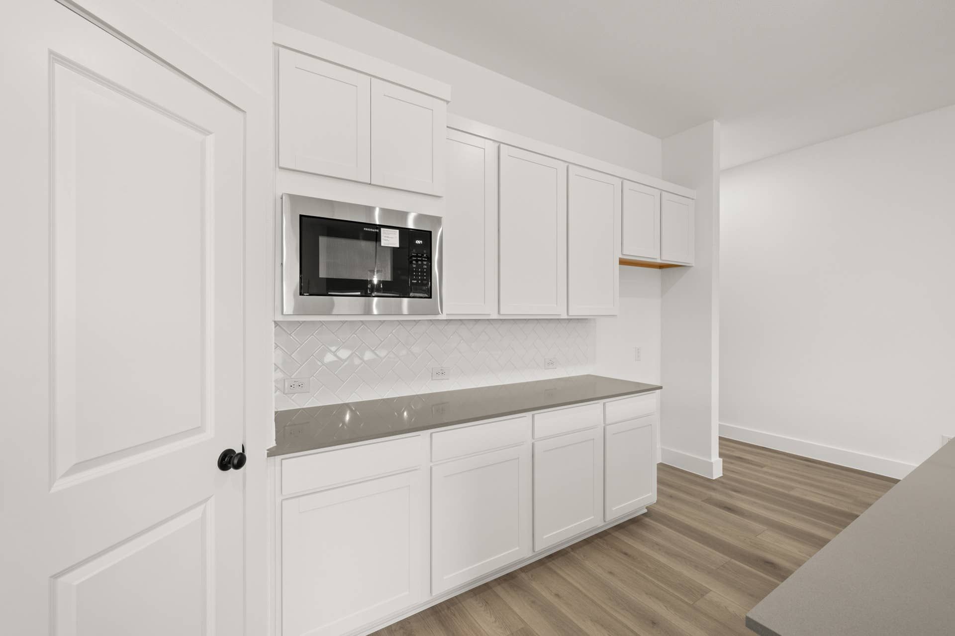 Modern kitchen with white cabinetry, microwave, and sleek countertops.