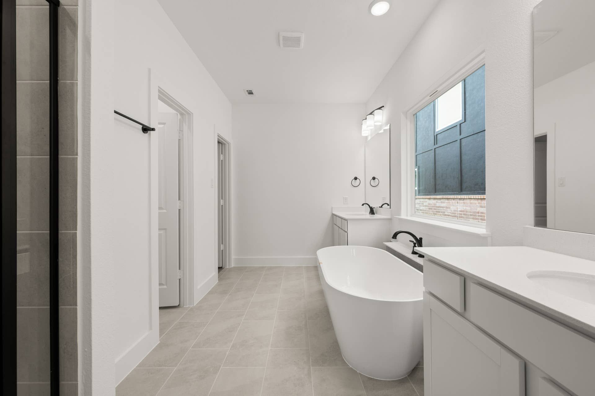 Spacious modern bathroom with freestanding tub, double vanity, and large window.